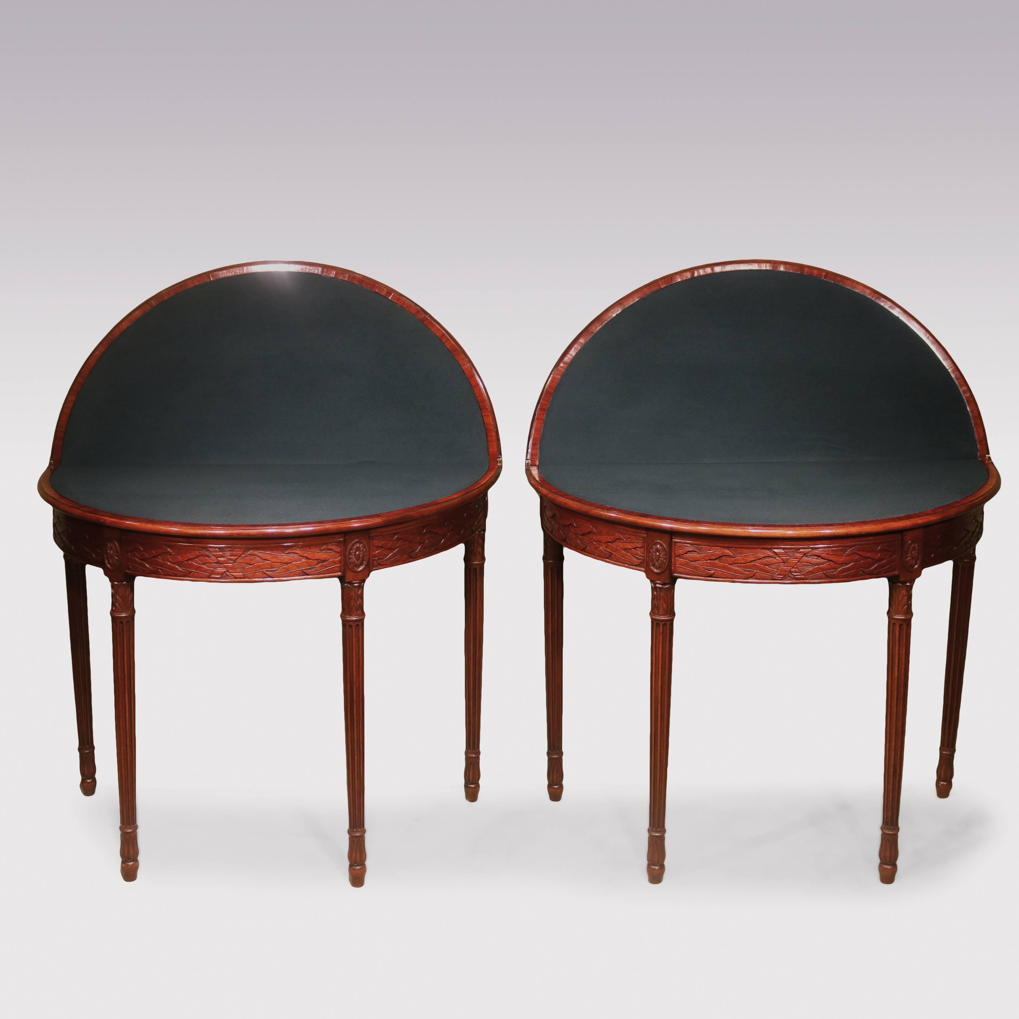 A pair of late 18th century flame figured mahogany card tables, of attractive small proportions, having ebony strung crossbanded demilune moulded edge tops, above unusual leaf carved panels to the friezes, flanked by oval paterae, supported on