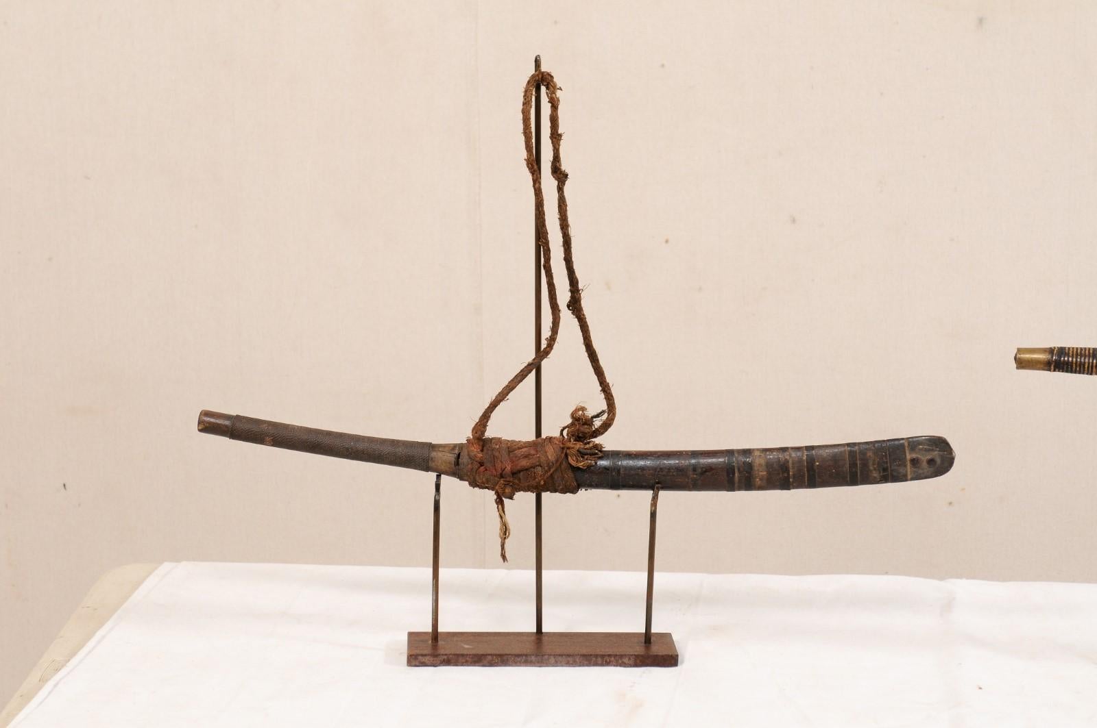 A pair of Laos swords from the late 19th century on custom stands. This pair of antique swords from Laos, often referred to as a daab or dha, were quick commonly hung by the front door of households throughout Southeast Asia, were often decorated