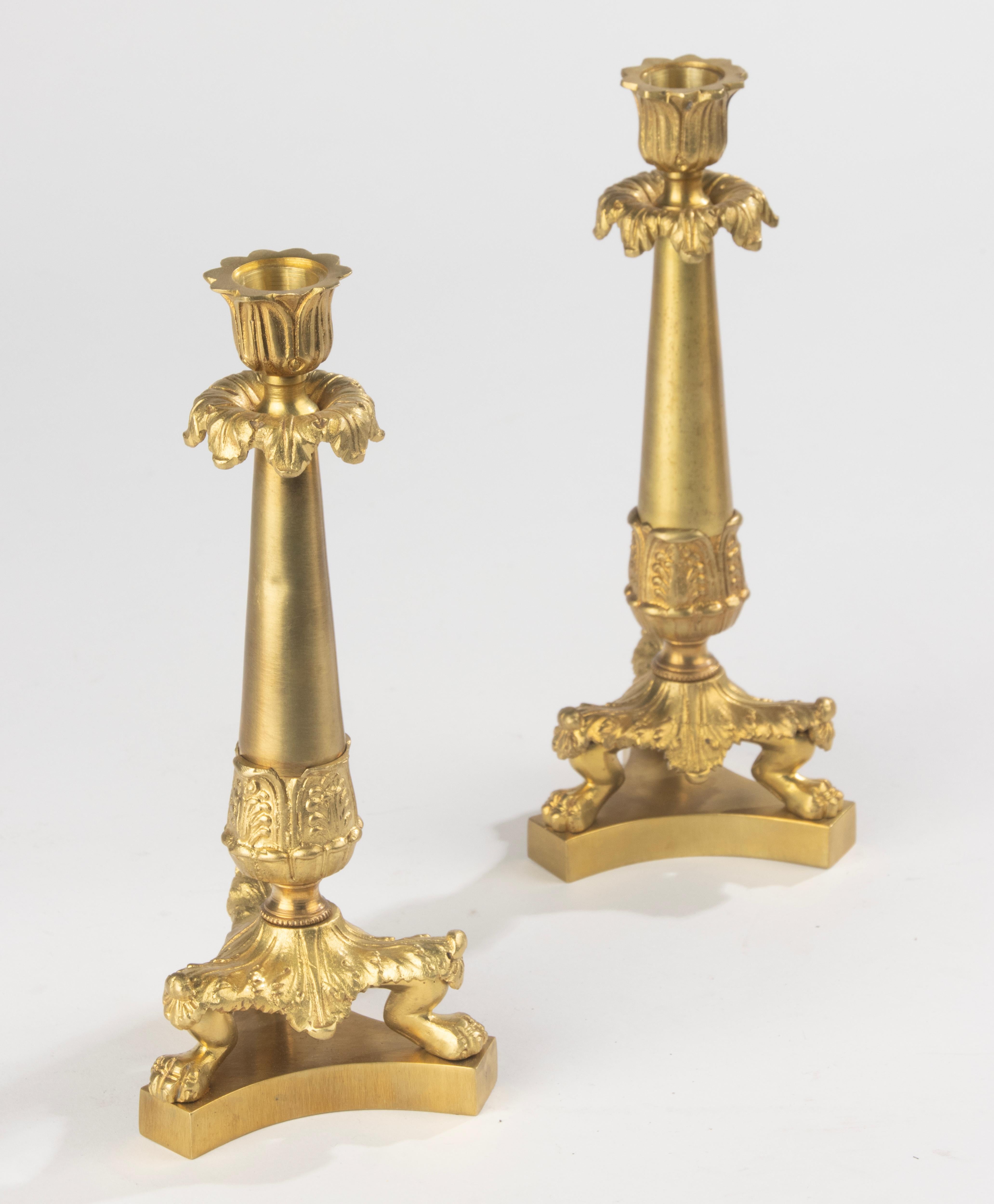 Elegante pareja de candelabros franceses de bronce dorado, hacia 1880. Estos candelabros finamente fundidos presentan una columna cónica con una detallada ornamentación foliada, que descansa sobre una base trípode con patas de garra. Un conjunto