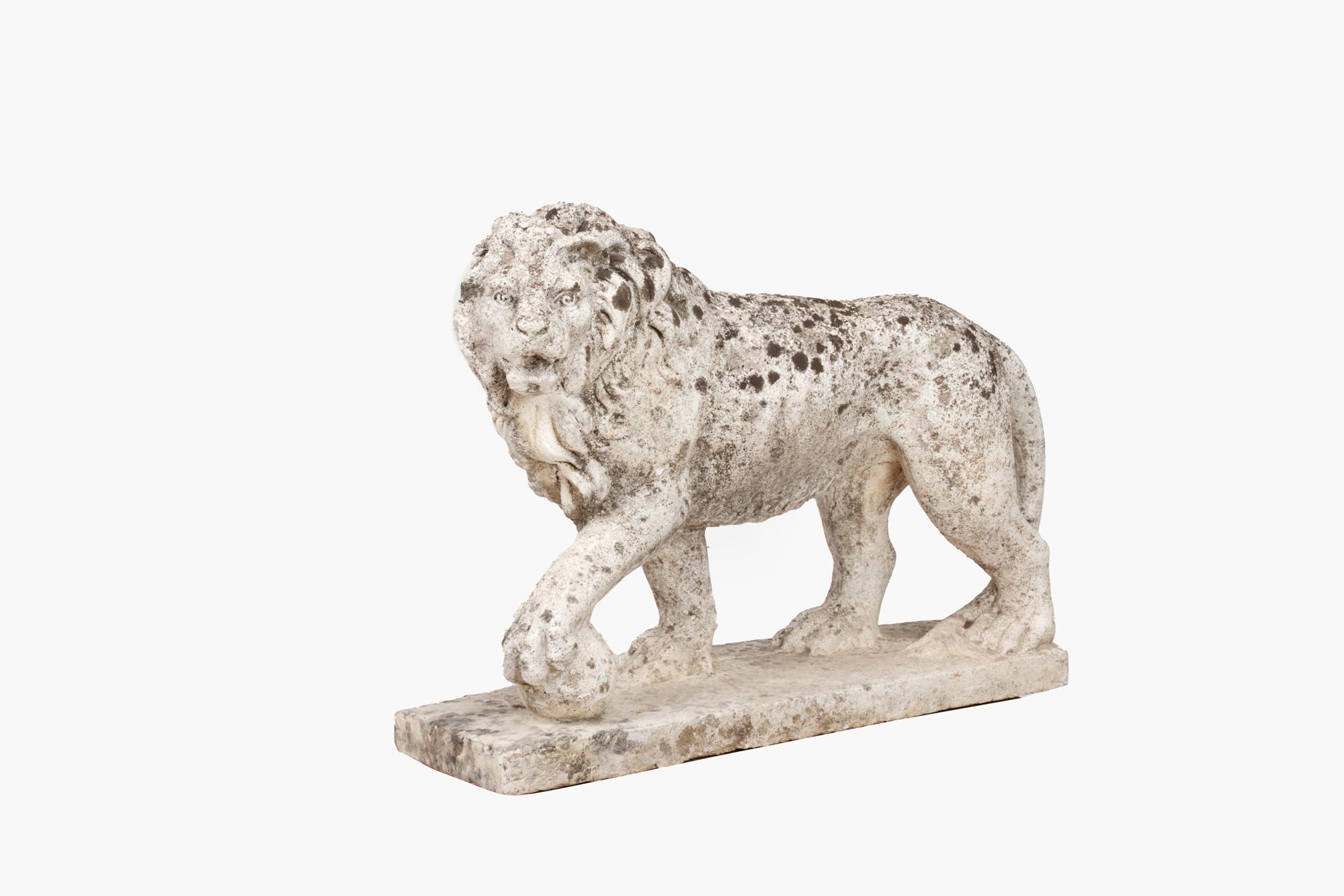 Pair late 19th Century carved composite stone lions in the classical style. This pair, both with a well weathered patina, are posed facing left and right with their front feet resting on a globe – a symbol of power. They are mounted on simple