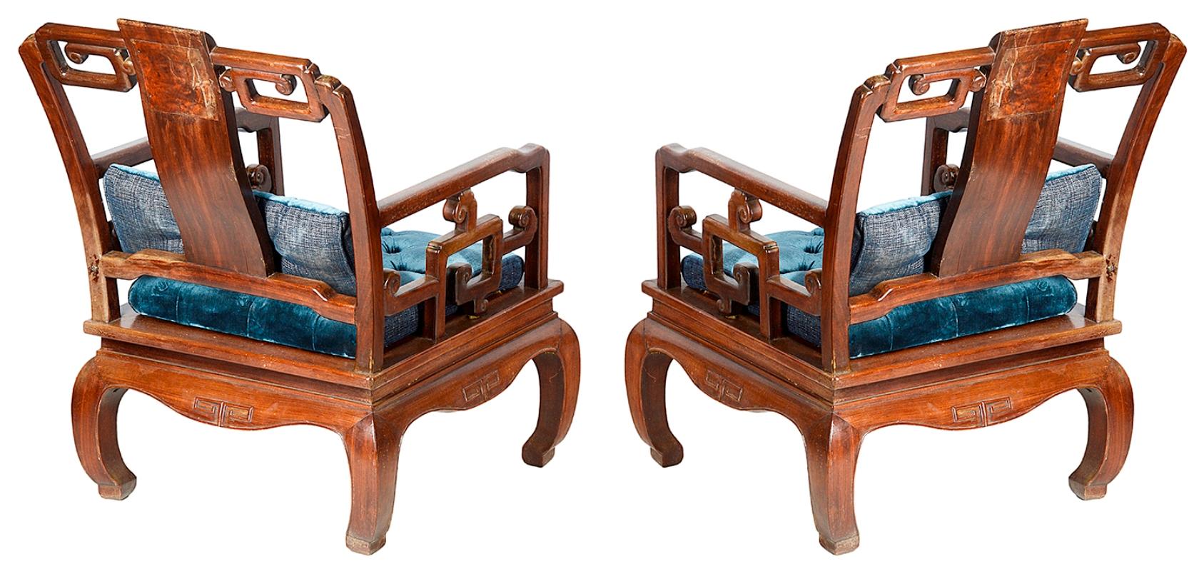 An unusual pair of late 19th century Chinese hardwood armchairs, each with inset blue and white porcelain panels, scrolling pierced decoration, blue velvet upholstered cushions, raised on scrolling carved legs.