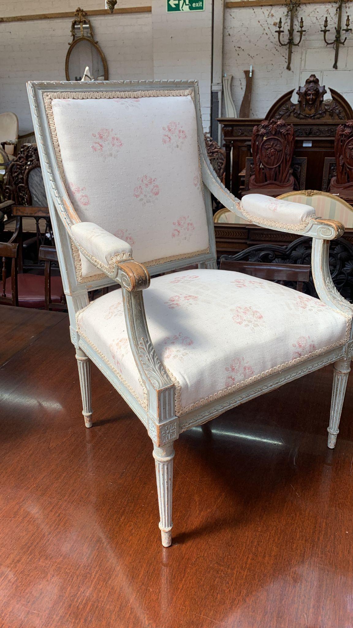 Pair of French late 19th Century carved and white painted Louis XVI style arm chairs with scrolling decoration to the arms and raised on round turned tapering legs.