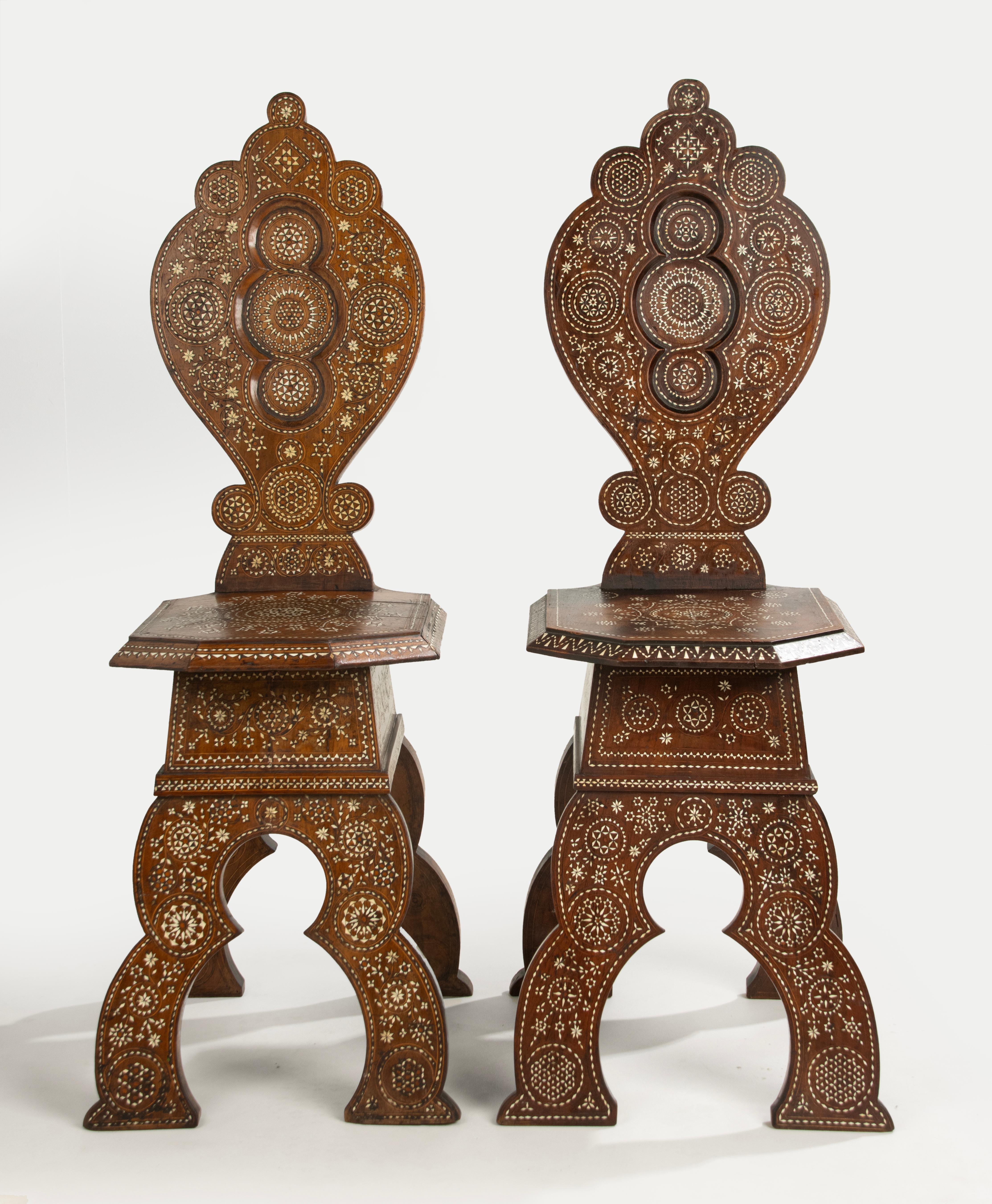 A pair of Syrian inlaid hall chairs, with scalloped backs and geometric inlay design.

Beautiful intricate inlay work with bone. 
Small difference in colour, Small different in the design of the inlay pattern. Some small piece bone missing.