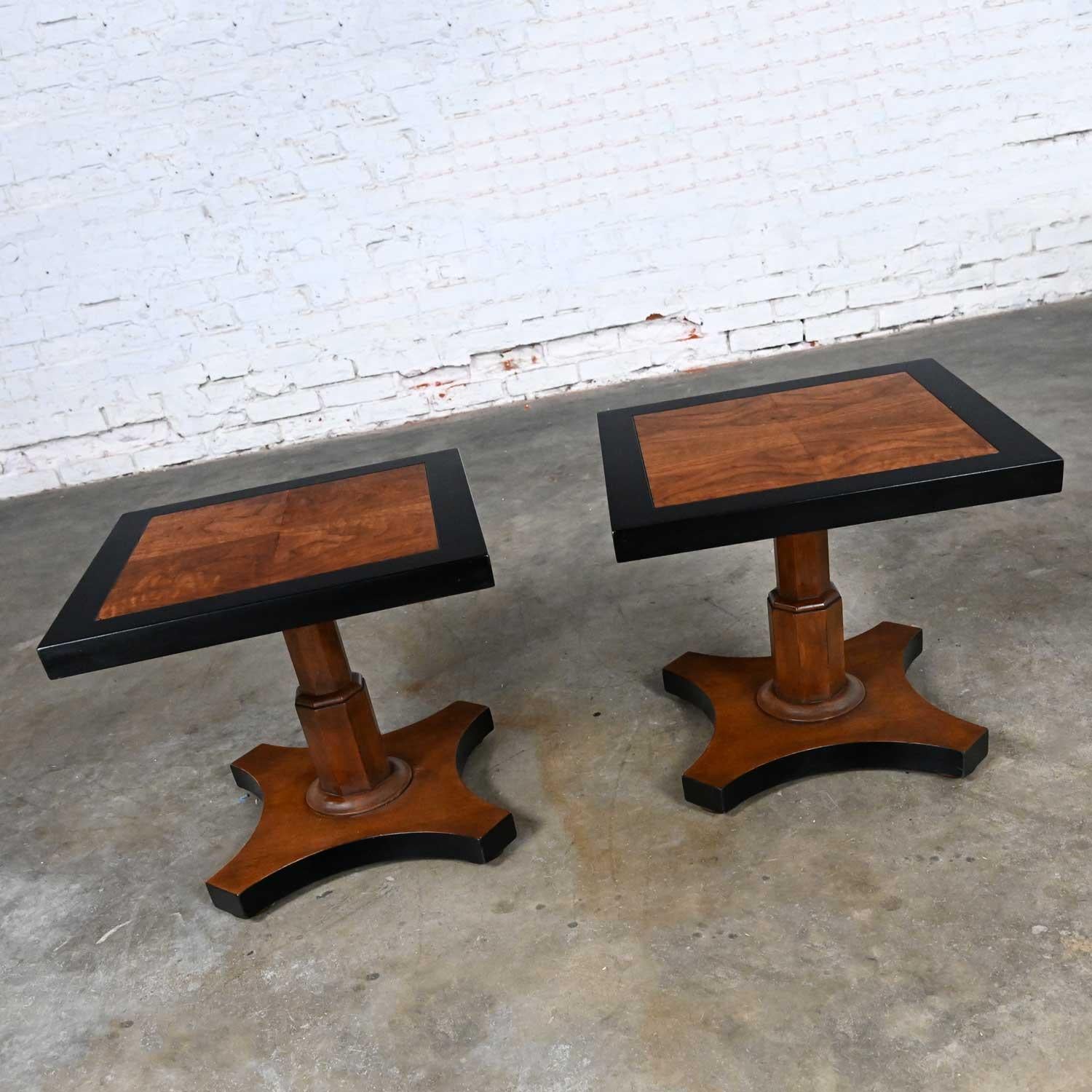 Fabulous Vintage Baker furniture campaign style pedestal end tables, a pair with a black and natural finish. Beautiful condition, keeping in mind that these are vintage and not new so will have signs of use and wear. The framed edges of the tabletop