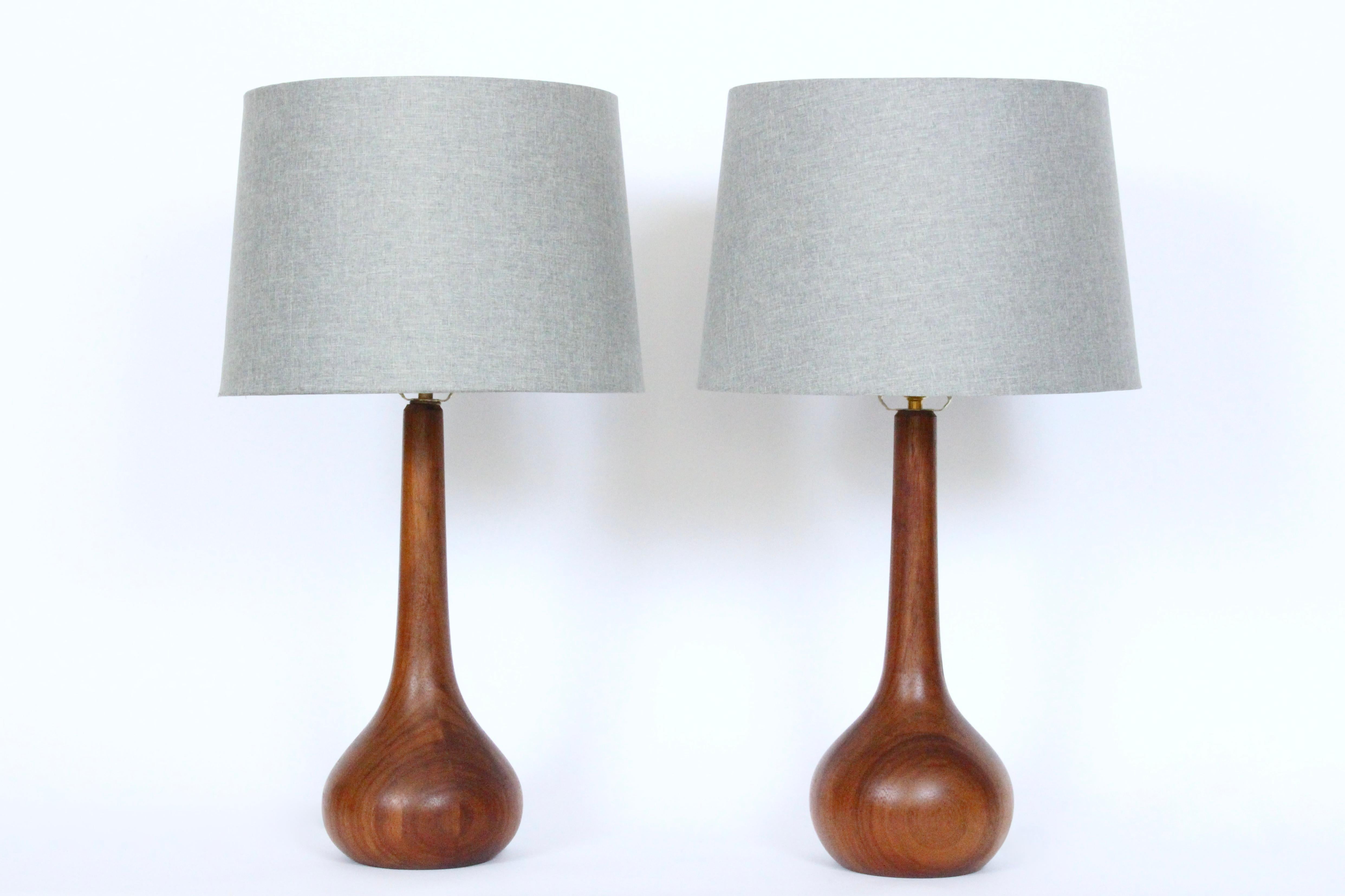 Pair of American Danish Mid Century Laurel Lamp Co. style teak table lamps. Featuring a pear shaped form in solid, stacked turned Teak. 16H to top of Teak. 19H to top of Socket. 27H to top of Finial. Shades shown for display only and not for sale