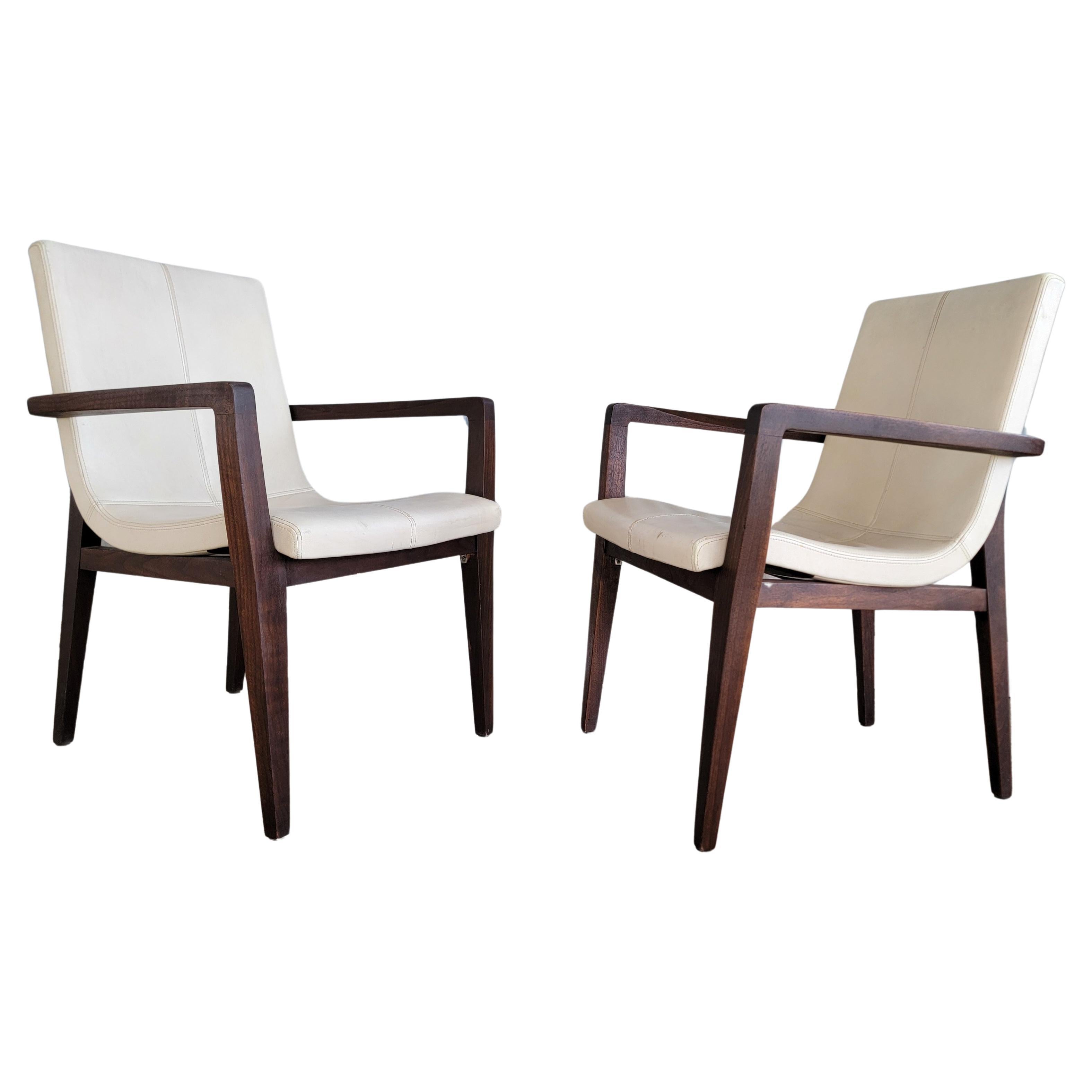 A pair of leather Siren dining armchairs by Holly Hunt. Scoop seat design. Retaining Holly Hunt metal label. Original leather upholstery in good condition, but does have light scuffing and minor wear. Hardwood frames may have been touched up or