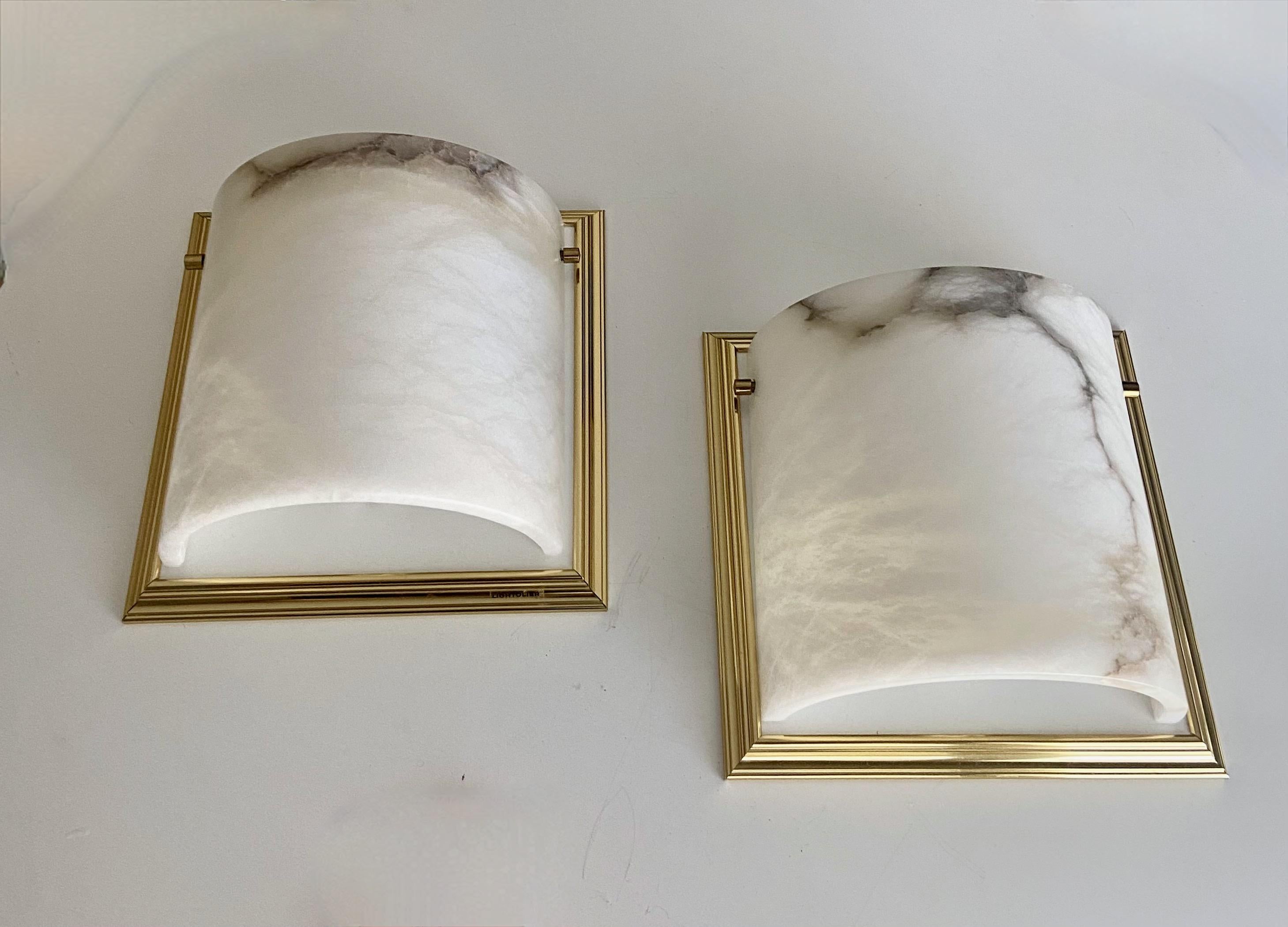 Pair Lightolier curved alabaster wall light sconces with brass fittings and brass plated trim backplates. Each uses single 60 watt regular A size bulb. Second pair available.