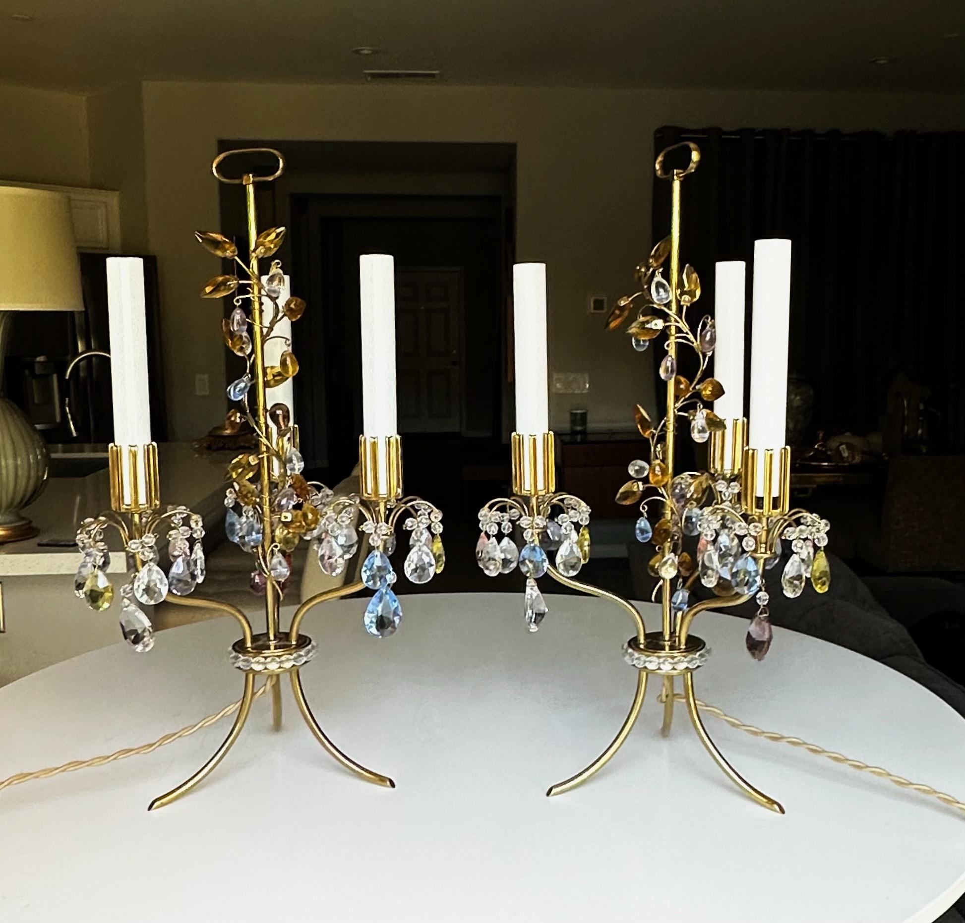 Paire de lampes de table Lobmeyr à trois lumières, conçues à l'origine par Oswald Haerdtl pour l'Exposition universelle de Paris en 1937. Composée de cristal taillé délicat et de manchons de bougie en laiton de forme unique sur un cadre léger et