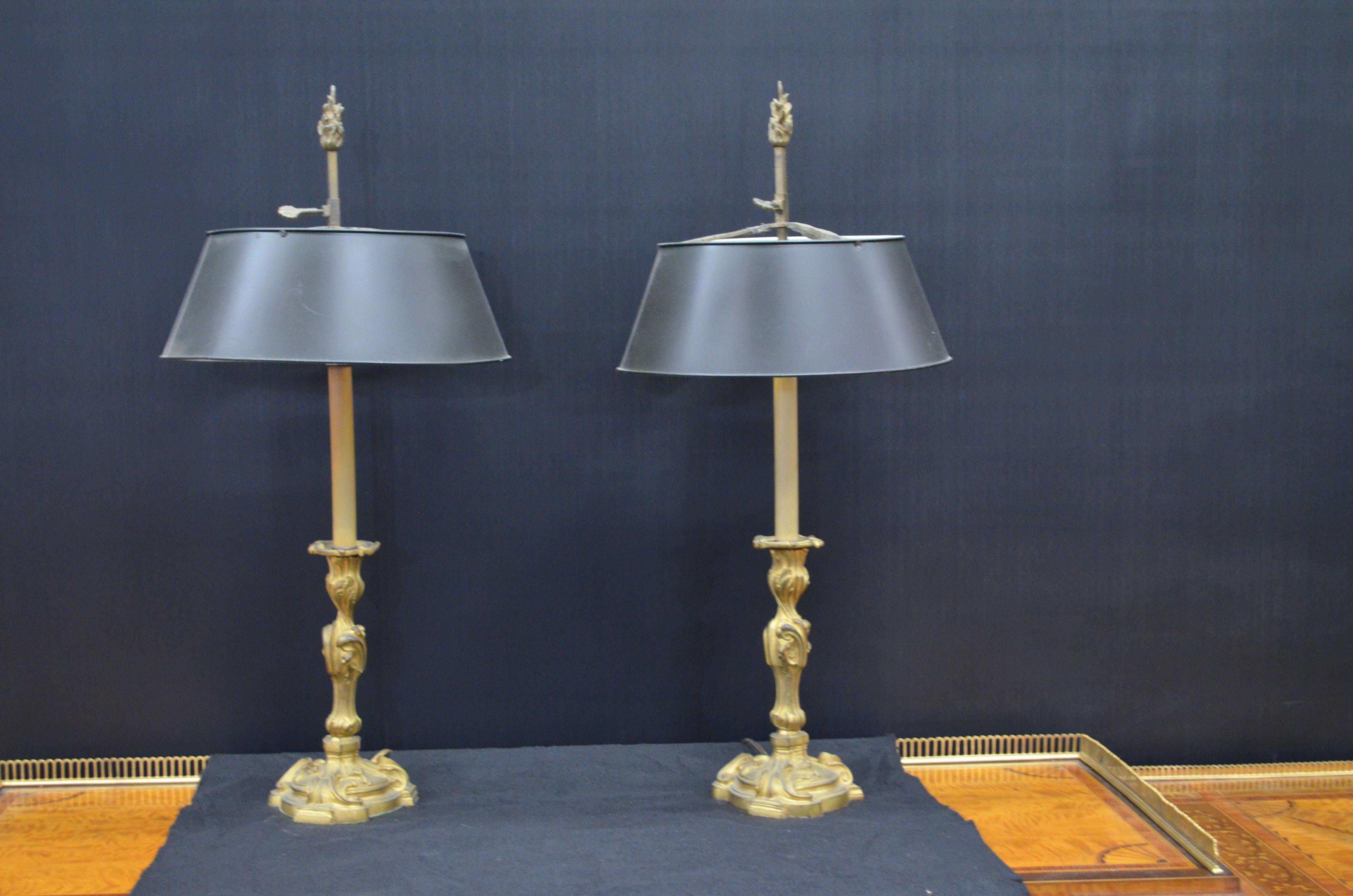 Paire de chandeliers en bronze Dore' de style Louis XV, montés en lampe, avec abat-jour en tôle bouillotte peinte en noir. Les chandeliers en bronze doré de style Louis XV ont une base surélevée circulaire triplement festonnée. Les tiges centrales