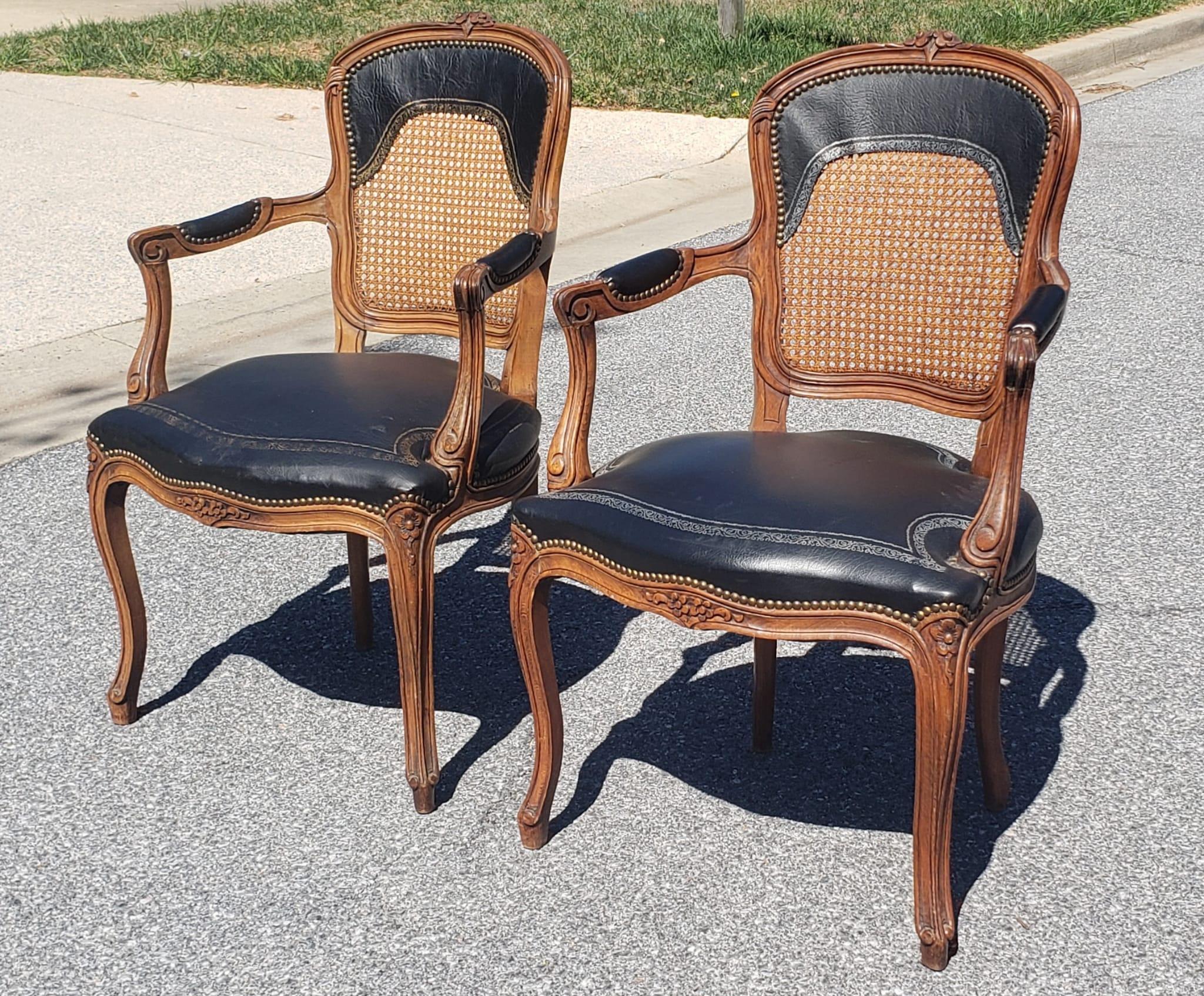 Pair of Louis XV Style Fruitwood Brass Nail Studded Leather Upholstered Cane Back Armchairs. Very good vintage condition. Some fading on Stinciled gold trim and silver trims. 
Measure 24
