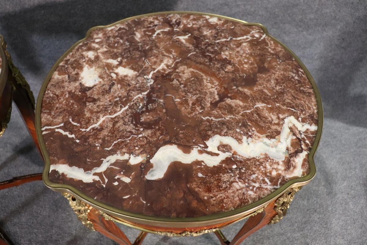 Paire de tables d'appoint en bois de roi montées sur bronze doré et bronze d'orfèvre de style Louis XV avec plateau en marbre. Un capuchon de pied manquant. Fentes dans le bois. Légères rayures de surface. Patine. Certains placages se