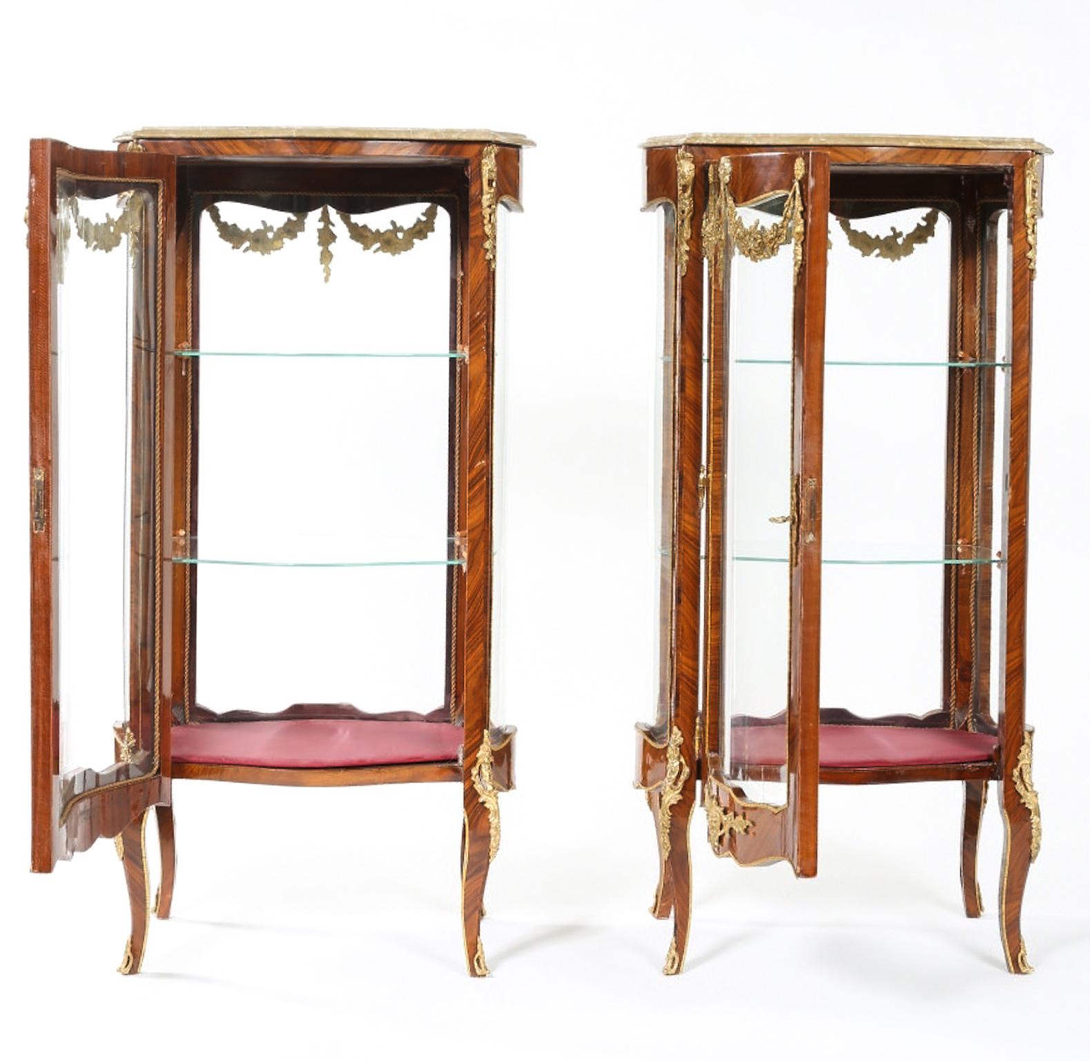 Pair of Louis XV style kingwood veneered vitrine with brass design details. Ormolu-mounted marble topped with glass shelves and bowed glass on all sides. Each one is very sturdy & in good vintage condition with wear appropriate with age / use. Each