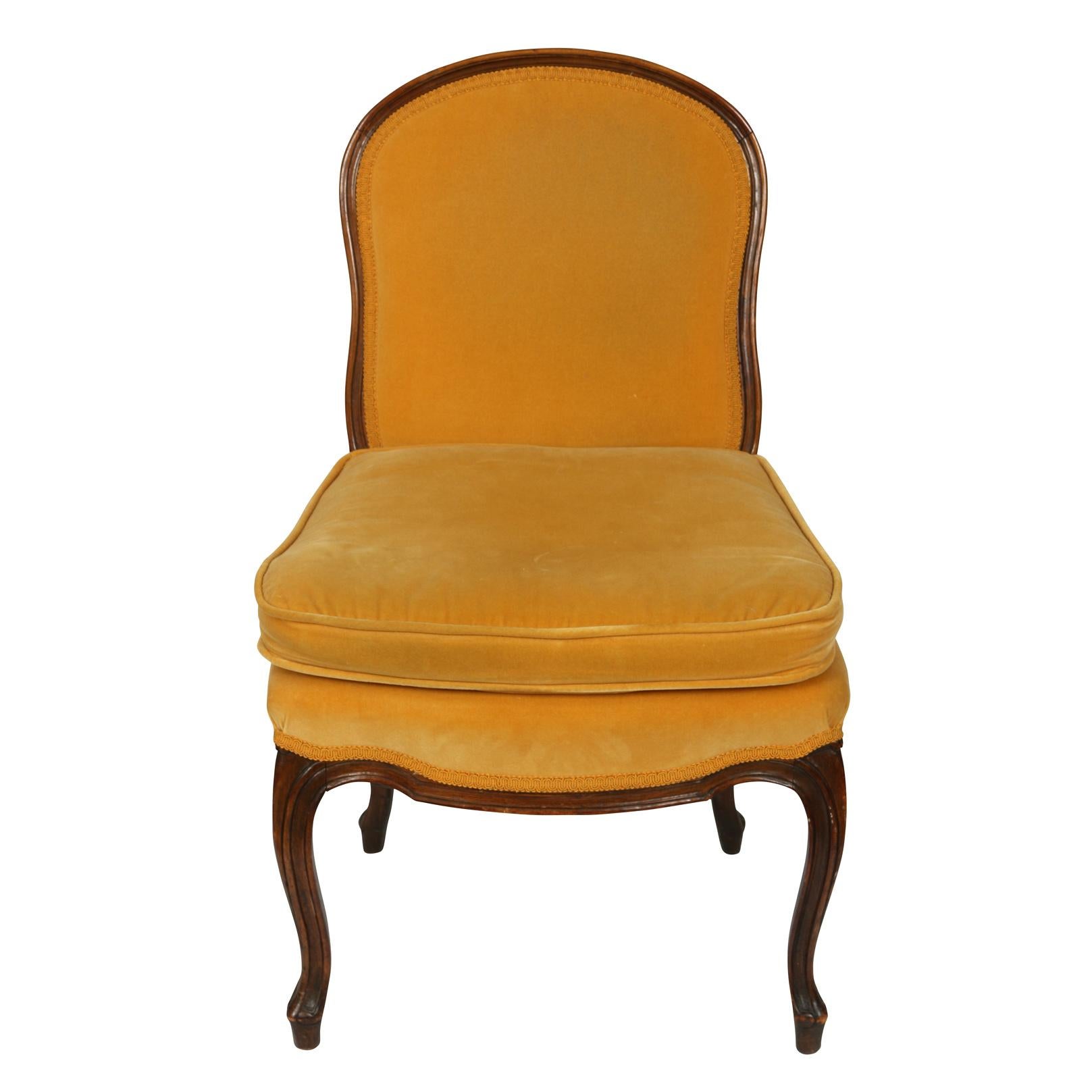 Pair of Louis XV style slipper chairs upholstered in ochre velvet with dark wood frame and legs.