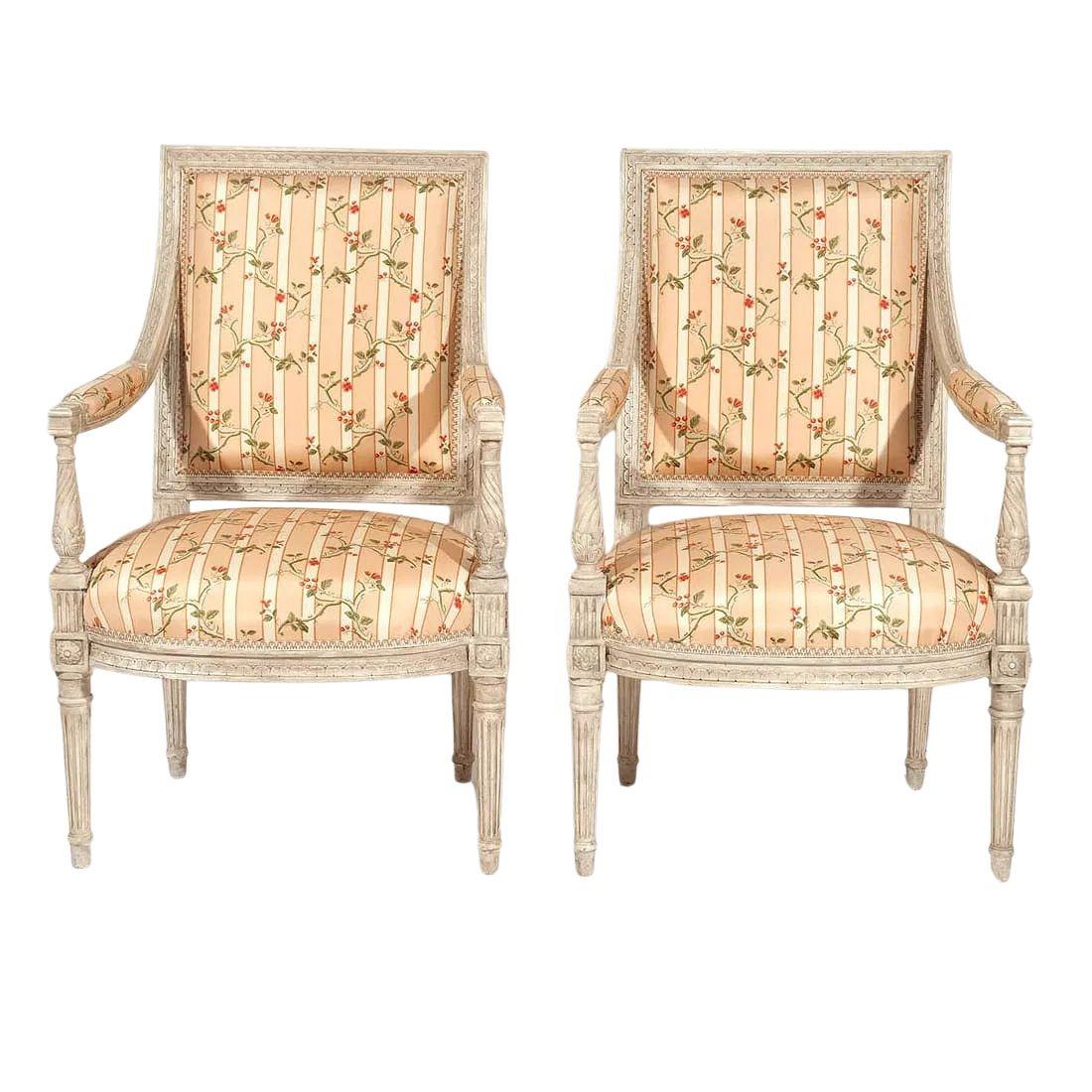 Paire de fauteuils peints et sculptés de style Louis XVI, illustrant l'élégance raffinée du design néoclassique français du XVIIIe siècle. Chaque chaise présente un cadre en bois délicatement sculpté et peint avec une patine douce, soulignant les