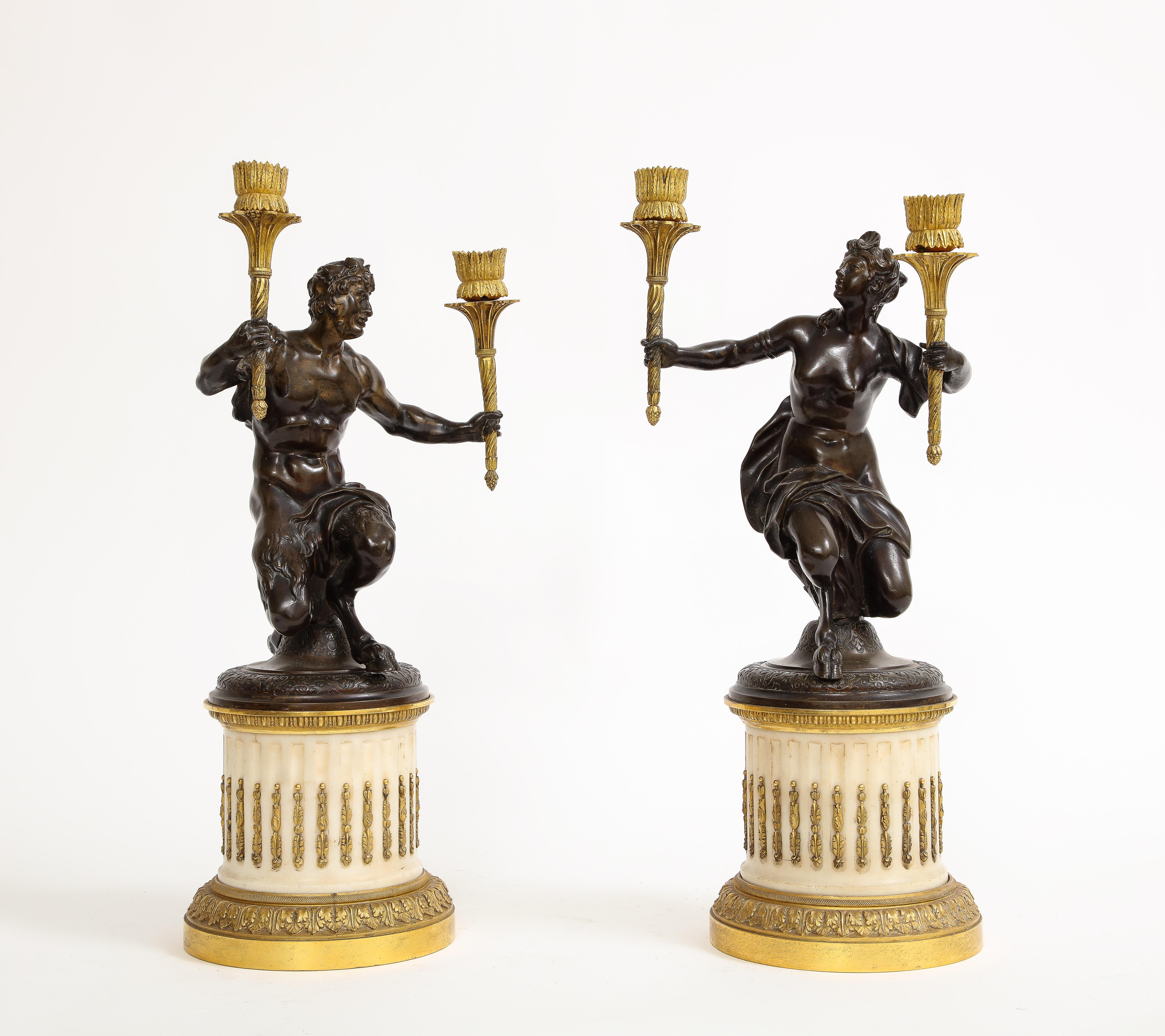 A n Exquisite Pair of Louis XVI Period Figural Patinated and Ormolu Candelabrum on Marble Plinths.  These remarkable candelabra epitomize the artistic splendor of the Louis XVI period. Inspired by the lively scenes of Bacchanalian revelry, the