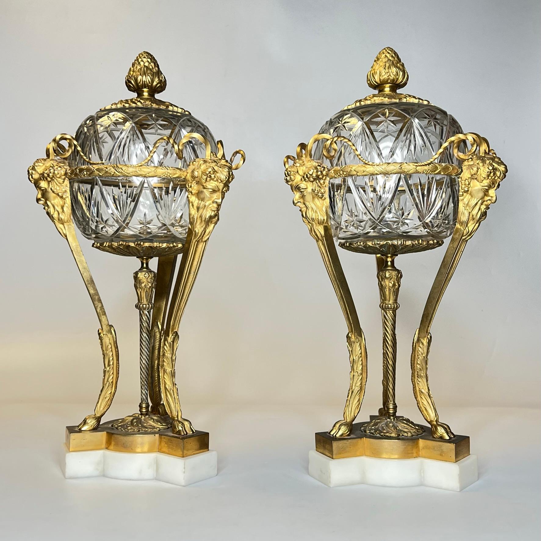 Our pair of cassolettes in the Louis XVI style have the form of neoclassical atheniennes crafted from gllt bronze mounted to cut white marble pedestals, and feature finely cut glass bowls and lids. Very good condition, with just a couple small chip