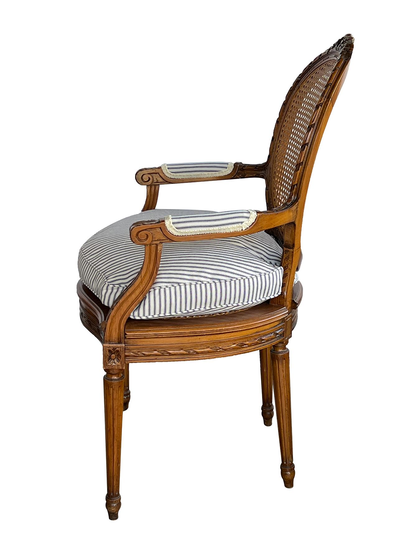 each of good proportion the ribbon crest above an oval caned back over a serpentine caned seat flanked by open arms; all raised on turned fluted supports ending in toupie feet