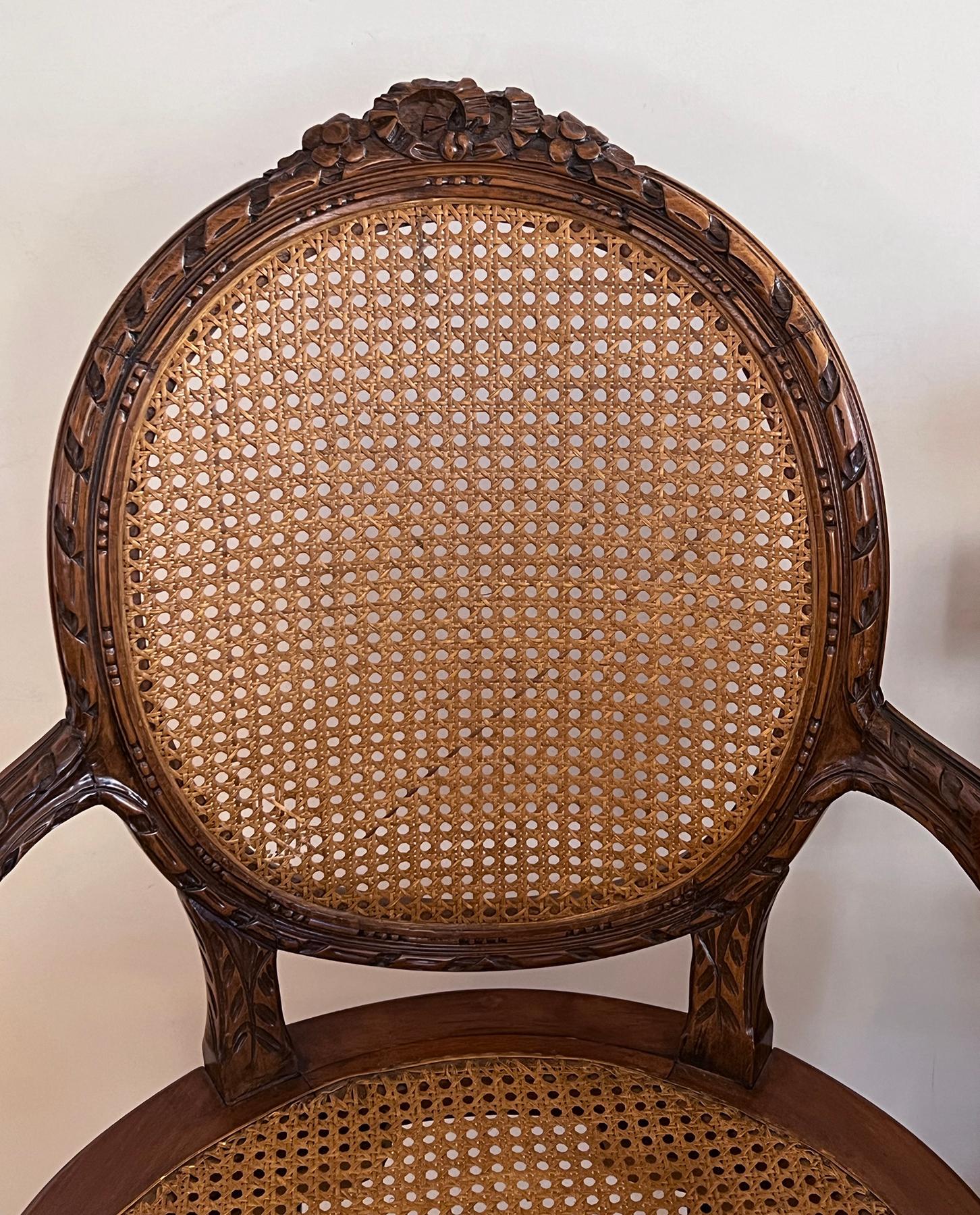 Début du 20ème siècle Paire de chaises à accoudoirs en noyer sculpté de style Louis XVI avec dossier et assise cannelés en vente