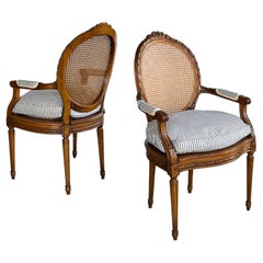 Pair Louis XVI Style Carved Walnut Arm Chairs with Caned Back & Seat