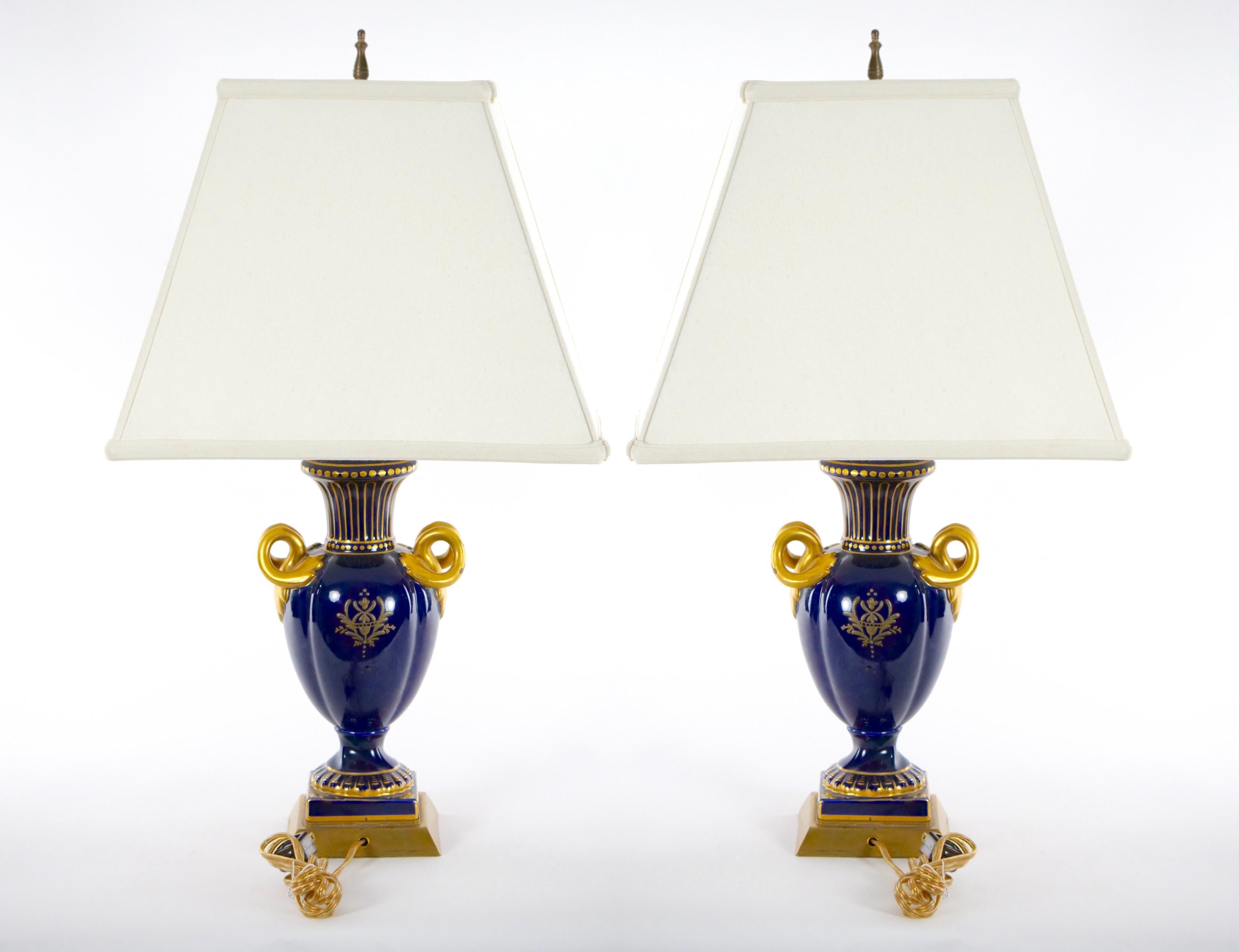 Early 20th century Louis XVI style French porcelain and hand gilt gold decorated urn shape vase pair table lamp. Each lamp features on one side a painted pastoral scenes decorated design. The reverse is a gilt gold painted with what appears to be a