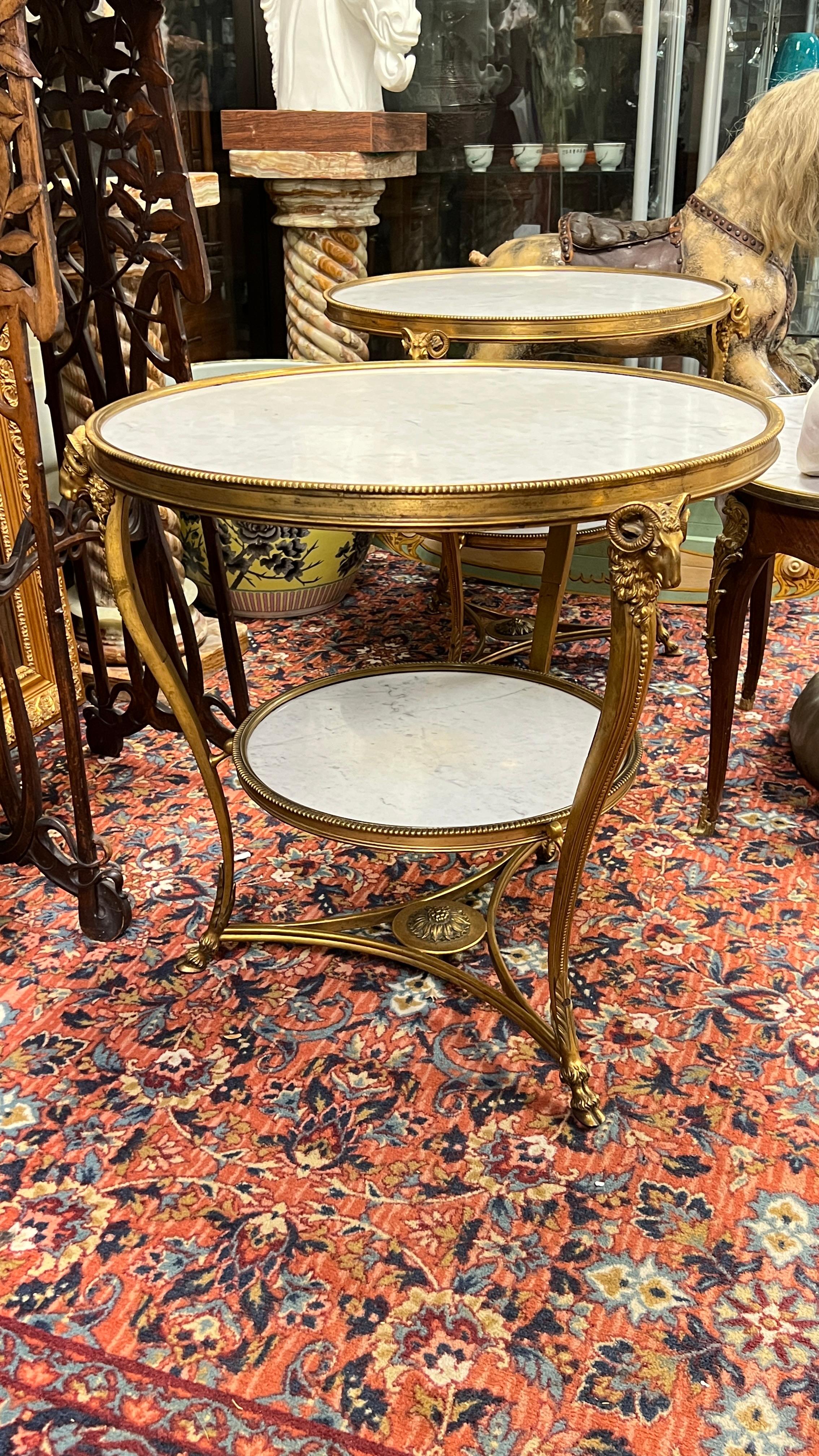 Pair of large  French mid century gueridons in the French Louis XVI stye with variegated white marble tops and stretchers, distinguished by its finely cast ram heads and hoof-form feet.
