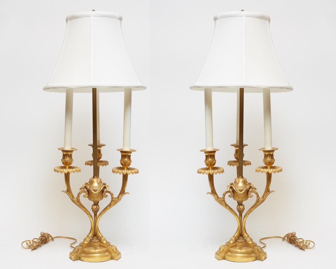 Zwei antike Kandelaber aus vergoldeter Bronze im französischen Louis-XVI-Stil, elektrifiziert mit modernen Fassungen, Kerzenabdeckungen und Kabeln, mit Eichelknäufen aus Zinn. Schattierungen sind nicht verfügbar.