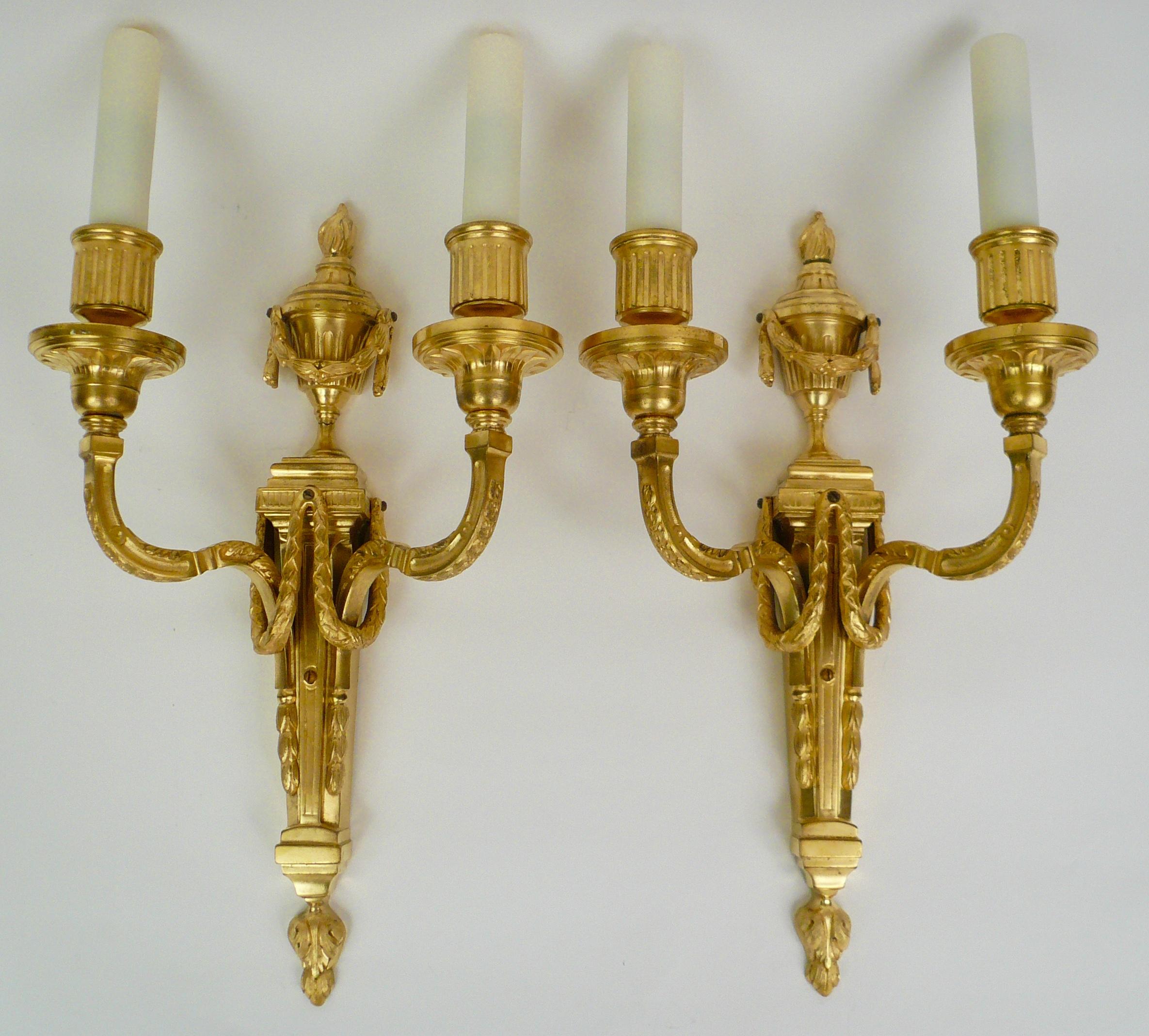 This finely details pair of Louis XVI style sconces feature Neo-Classical motifs including urns. swags and acanthus leaves. They retain their original gilding and are signed Caldwell.