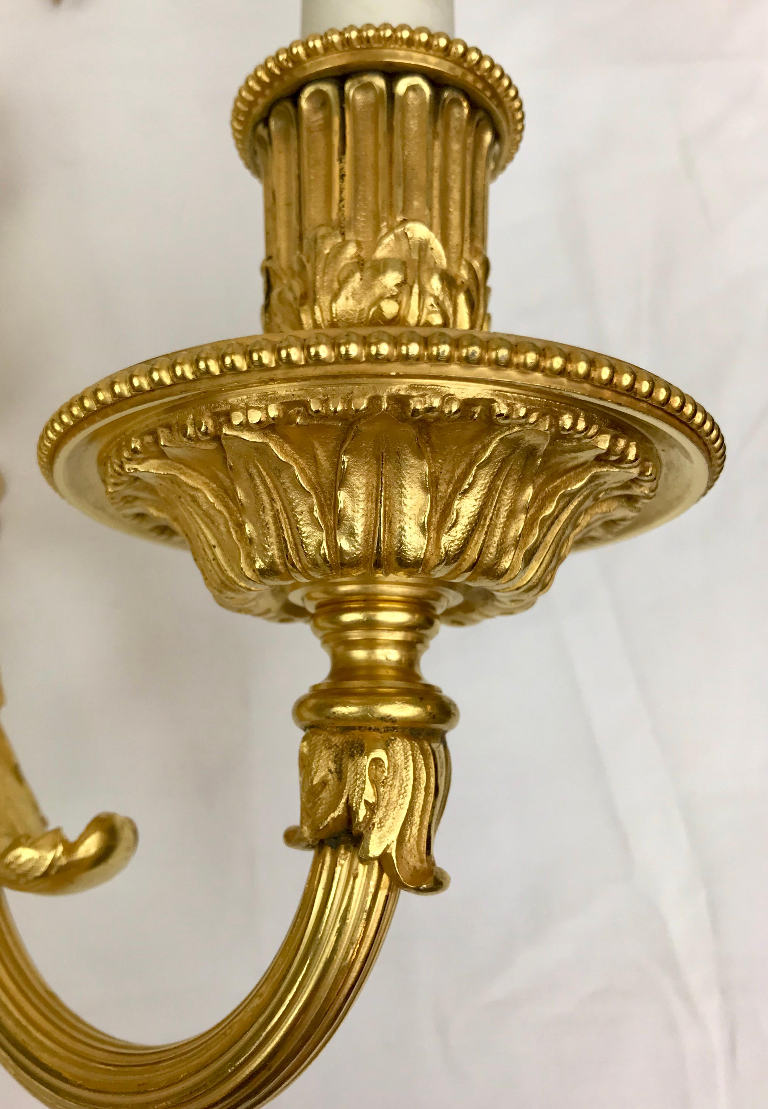 This fantastic quality pair of signed Louis XVI style gilt bronze sconces are by the renown marker Edward F. Caldwell. They feature Neo-Classical motifs including acanthus leaves, bowknots, and pinecone finials. 