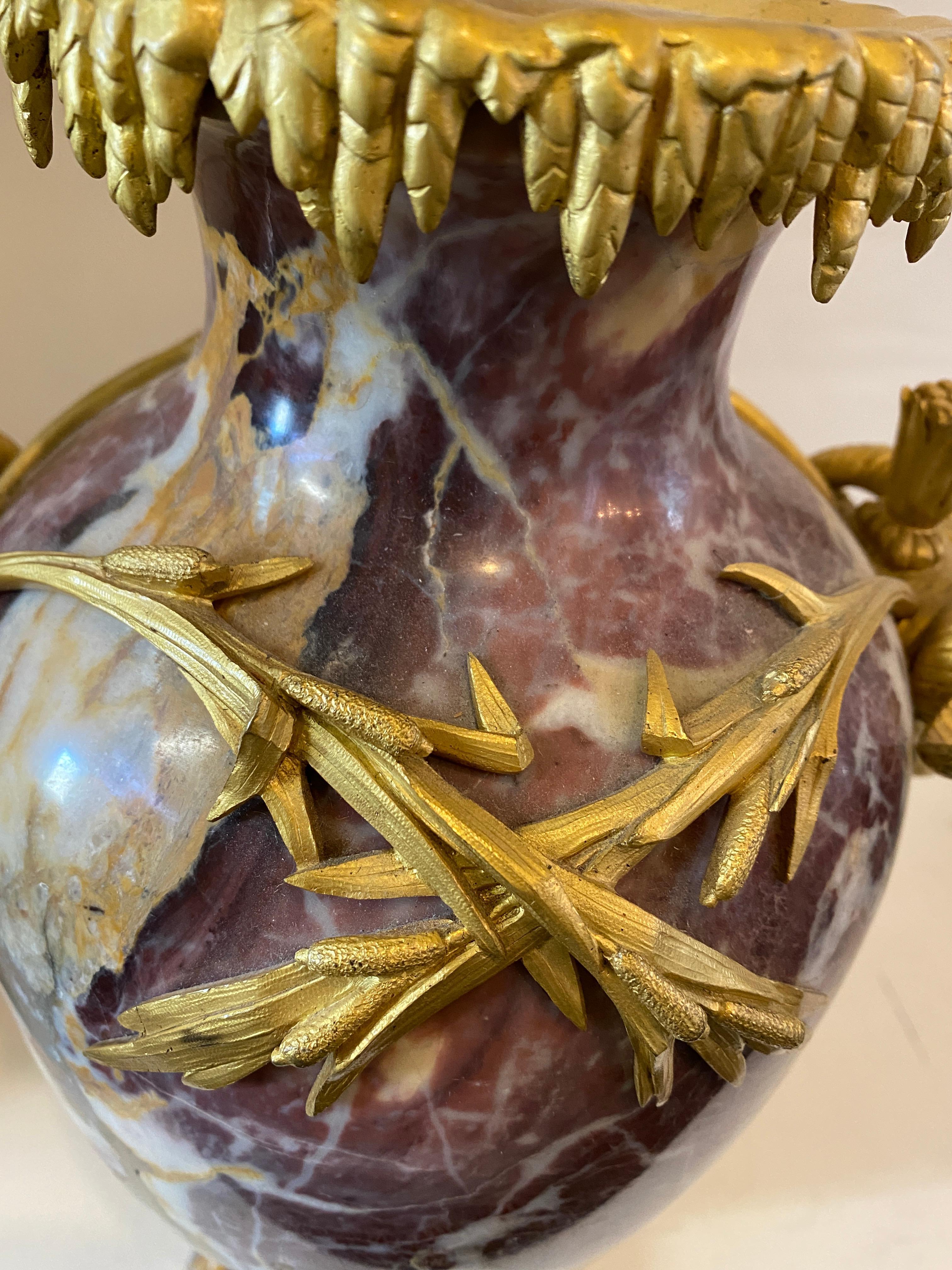 Coppia di gioielli in stile Luigi XVI con montatura in ormolu
Vasi in marmo di Breche, 
XX secolo, ciascuna a forma di urna affiancata da manici a testa di montone. 
Altezza 17 pollici.