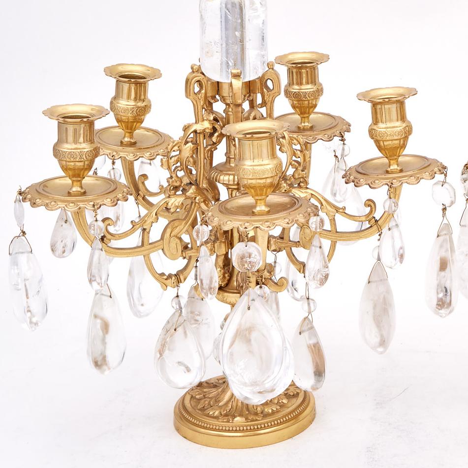 Pair of Louis XVI style gilt-bronze and rock crystal five-light candelabra. Each segmented stem with finial above pierced scroll-cast candle arms hung with pear-shaped prisms and continuing to a spreading foot. Measures: Height 25 1/4 inches (64
