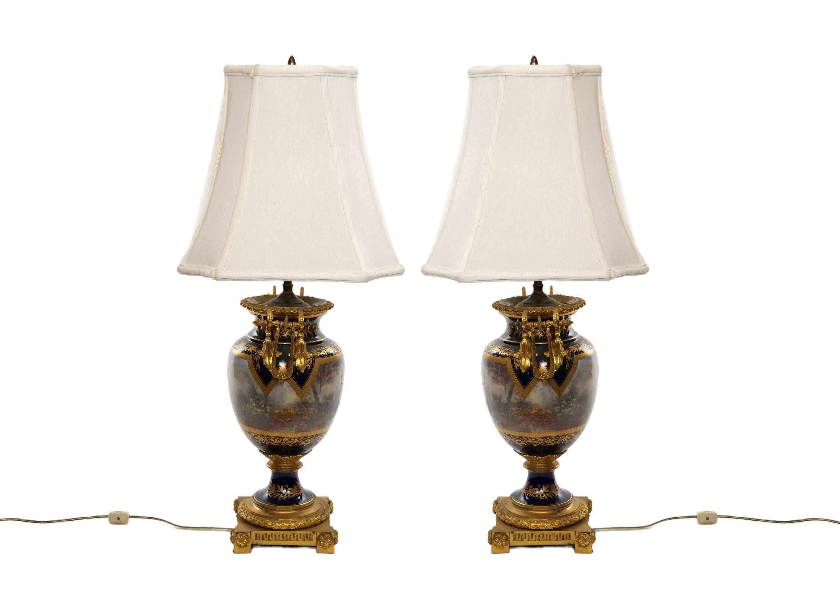 Louis XVI style French Sevres cobalt porcelain and dore bronze-mounted ormolu vases pair table lamp. One side is painted with pastoral love scenes signed by a famous artist in the mid 19th century. The reverse is painted with a different garden