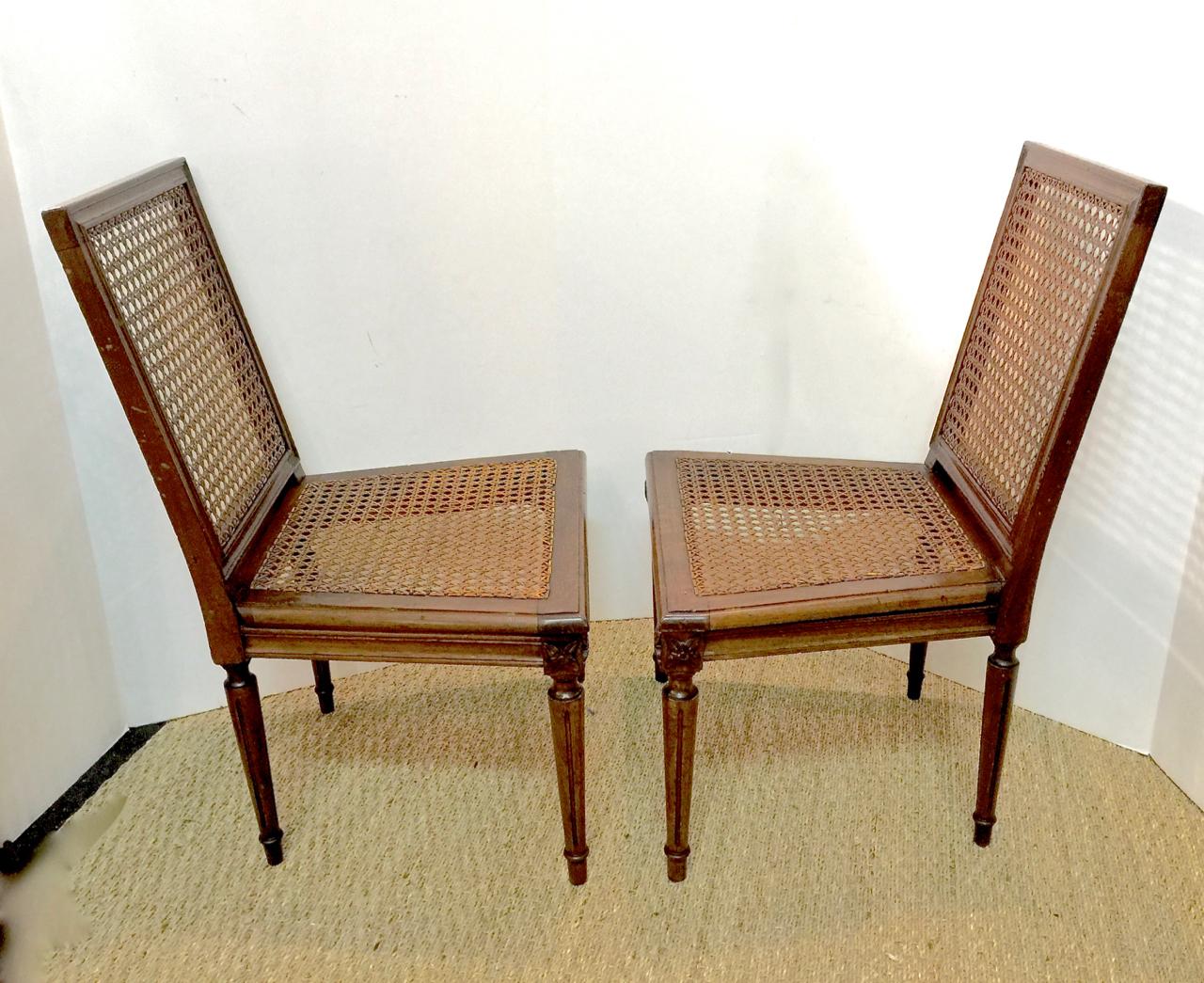 This is a wonder pair of mid-late 19th century Louis XVI style caned slipper chairs or fireside chairs in their original condition. The carved walnut frames retain their original caned seats and backs. Both chairs are in overall very good condition.