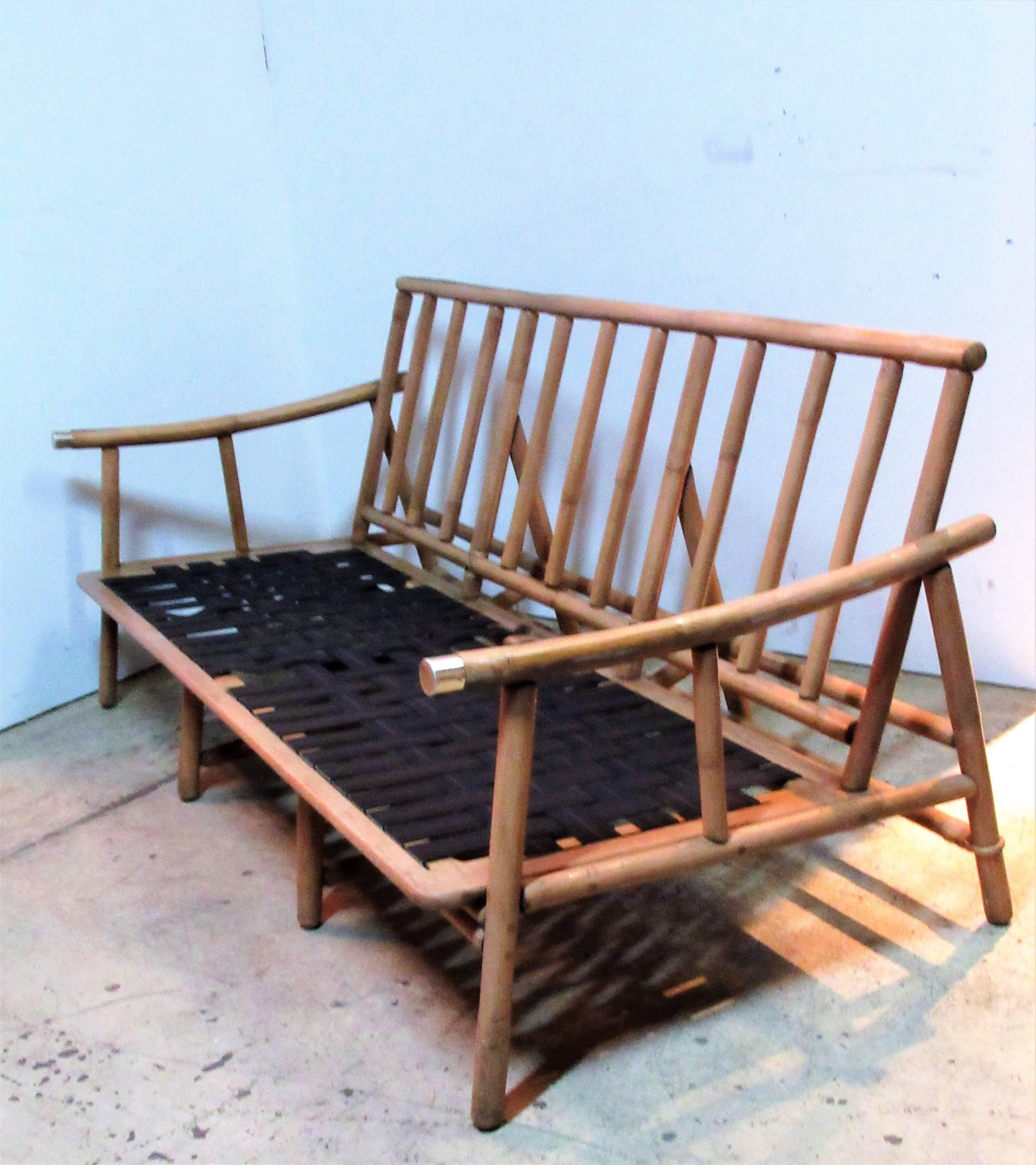 Un ensemble de trois pièces de mobilier en rotin conçu par John Wisner dans les années 1950 par Ficks Reed en bonne finition naturelle couleur miel - l'ensemble se compose d'un canapé de six pieds et de deux chaises longues assorties:: tous avec une