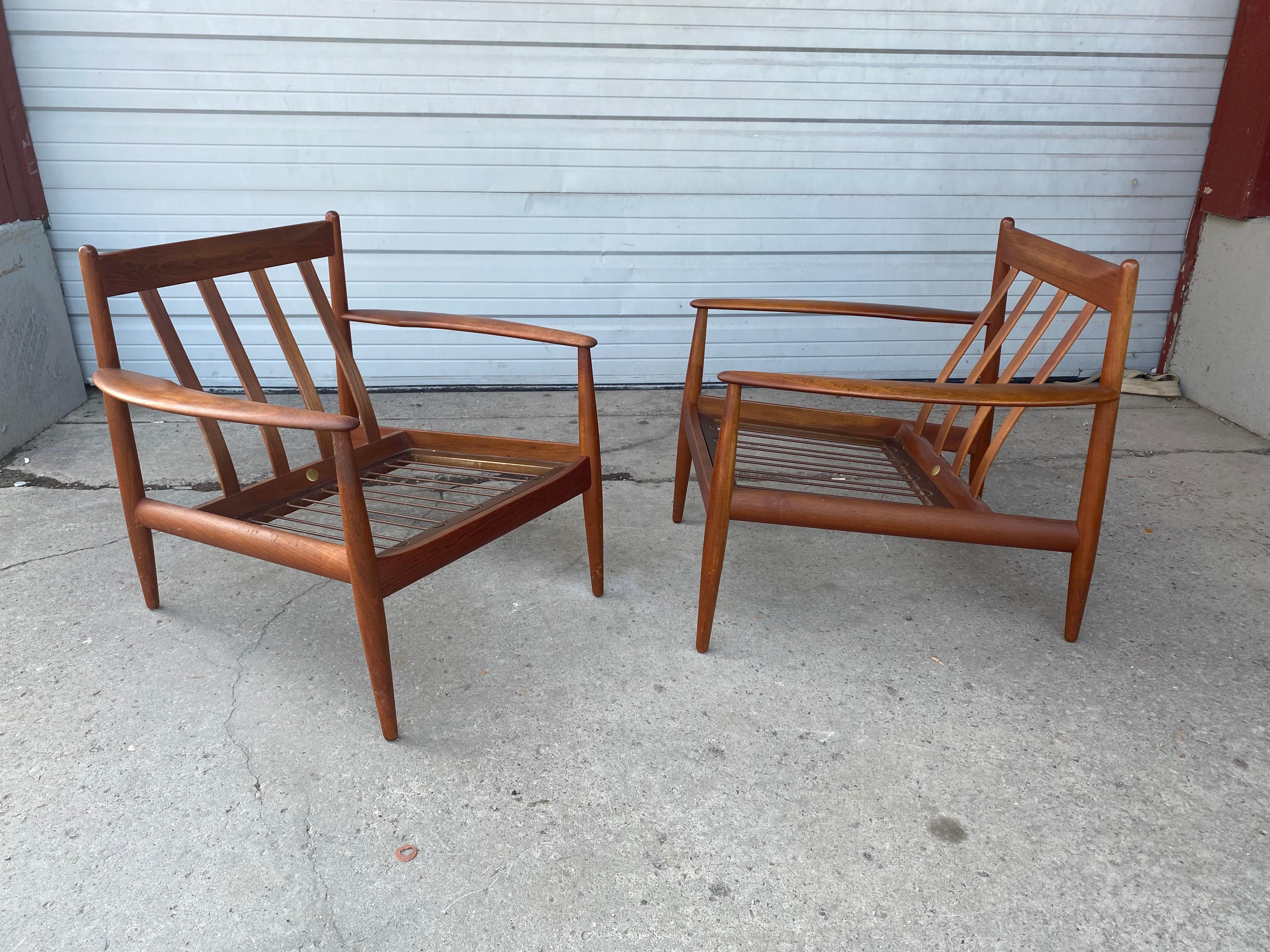 These are early and rare lounge chairs designed by Grete Jalk manufactured by France & sons..Solid Teak construction,,This pair includes original spring cushions.Superior quality and construction..Extremely comfortable,, Retains original early metal