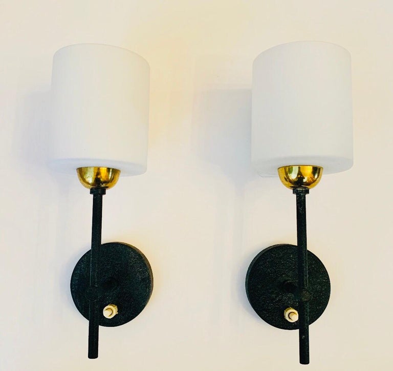 A pair of black enamel and polished brass sconces with white opaline shades. Newly rewired.