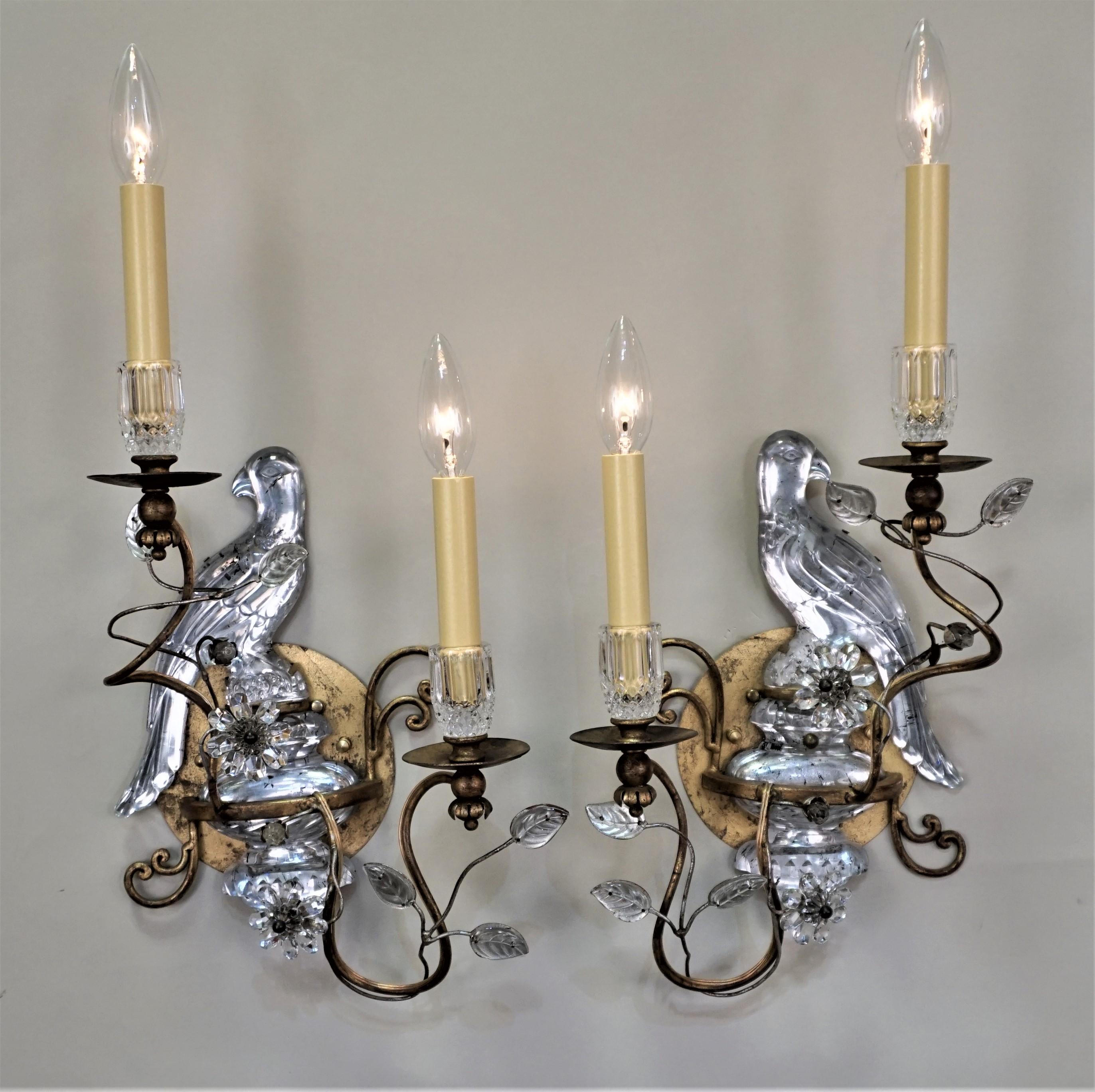 A stunning pair of gilt iron, touch of silver and crystal sconces by of Maison Baguès. These double light wall sconces feature the flower and leaf design with big bird as backplate.