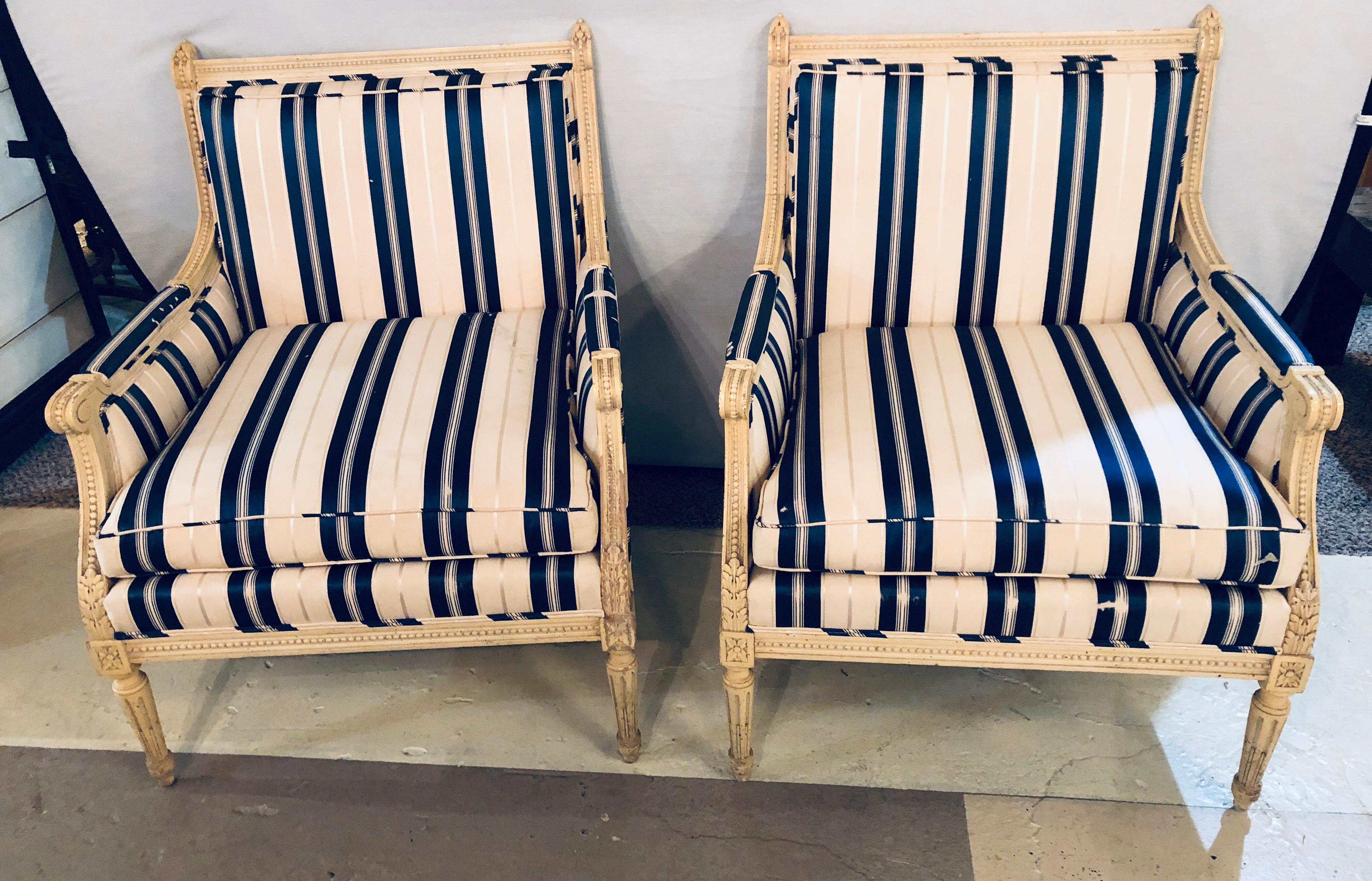 A finely carved pair of Marquis in a Swedish or Hollywood Regency Design. The sleek Louis XVI Style tapering legs supporting a wide and strong case of leaf and ball carvings on the entire frame. Each covered in blue and off white stripped upholstery.