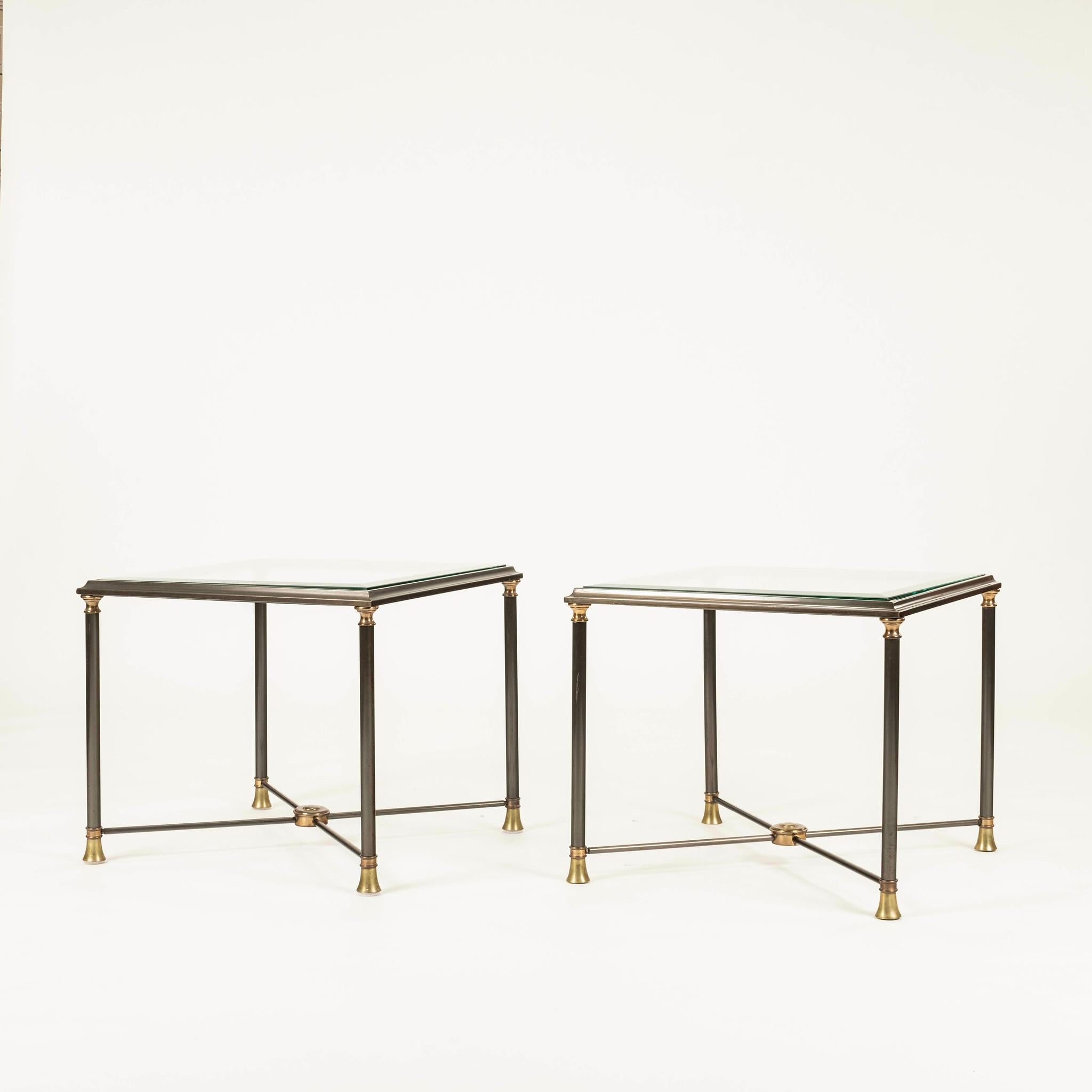Pair Maison Jansen style end tables featuring a steel frame with a glass top and brass accents.