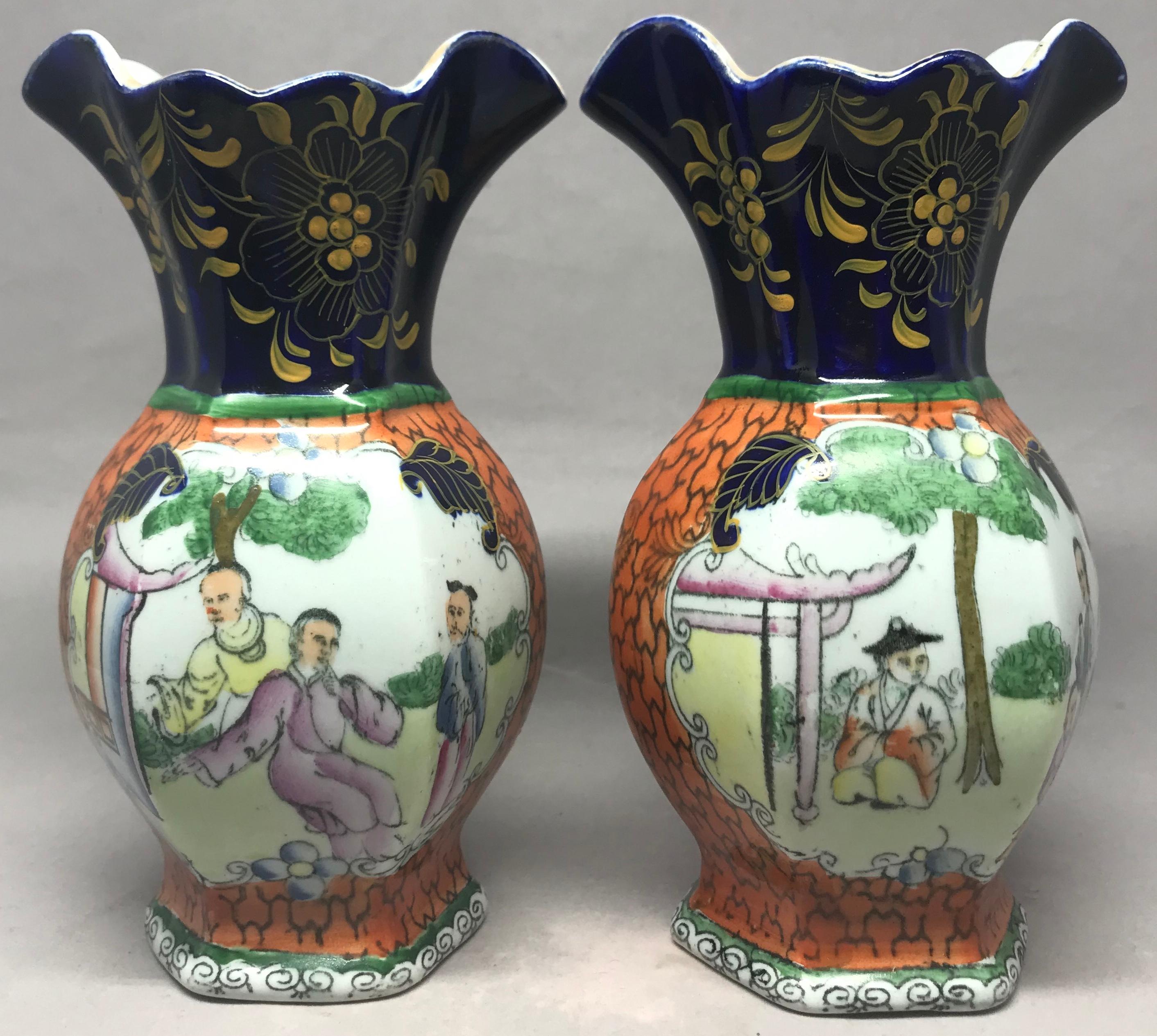 Pair Mason's chinoiserie vases. Small pair orange, blue, green and gilt baluster shaped Ironstone vases with central reveals depicting chinoiserie figures beneath dark blue and gilt floral decorated ruffled rims. Black printed marks for Mason's