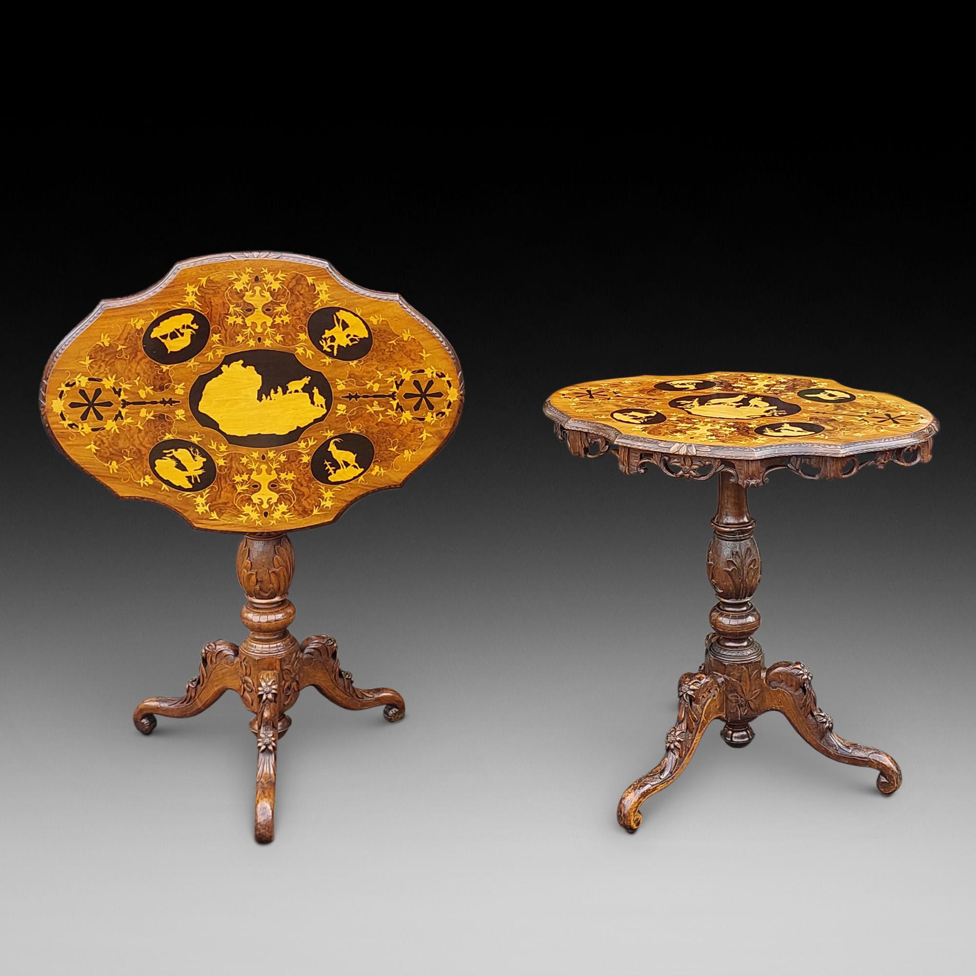 Pareja (emparejadas) de mesas auxiliares del siglo XIX con incrustaciones de marquetería y tilo de la Selva Negra, con tablero oval decorado con paisajes de íbices, gamuzas y ciervos de montaña sobre un friso de follaje perforado, columna de acanto