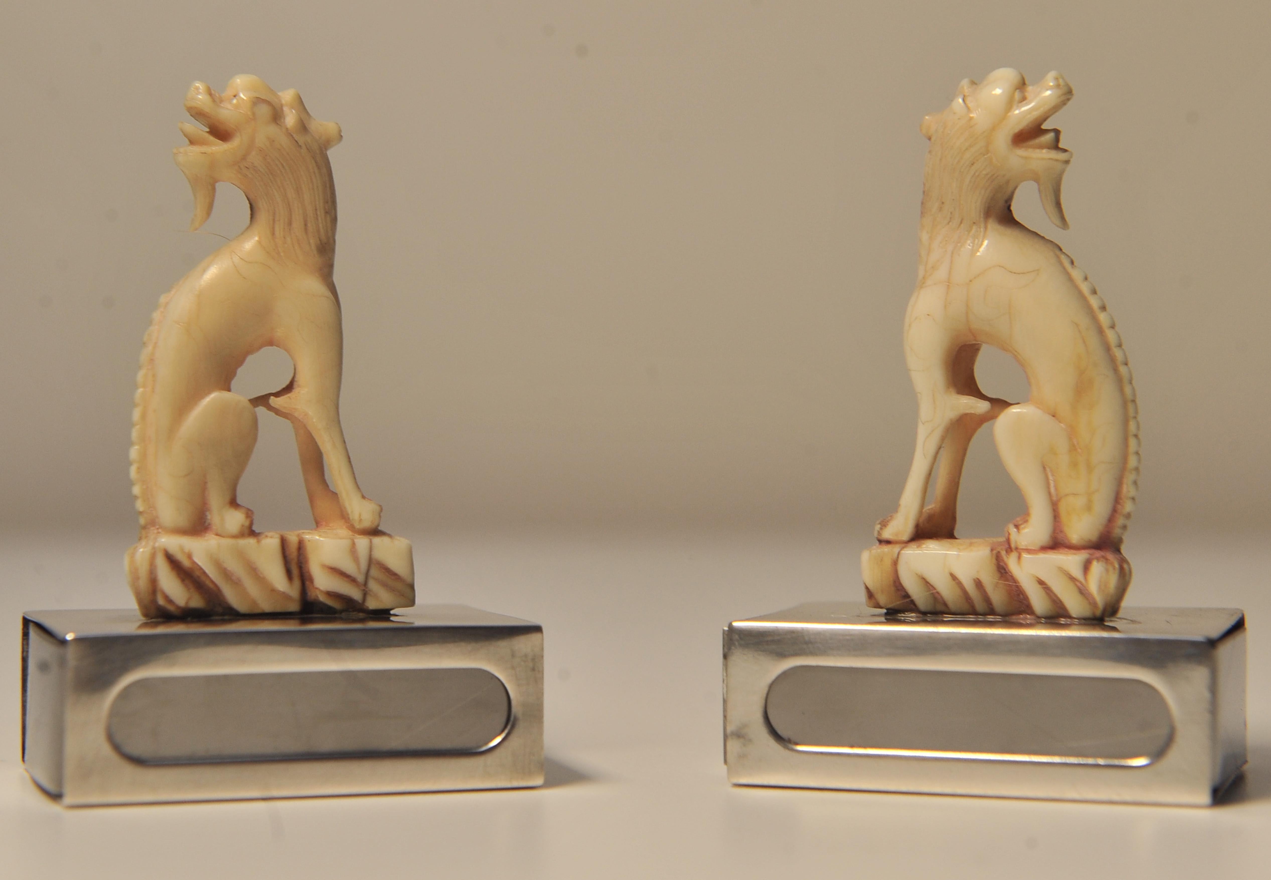 Délicate paire de porte-boîtes d'allumettes assortis en forme de chiens d'ivoire.
Les bases sont marquées d'un cachet d'argent.

Les lions gardiens chinois, ou lions gardiens impériaux, sont un ornement architectural traditionnel chinois, mais leurs