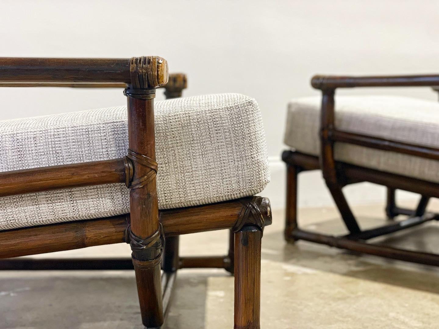 Pair of substantial mid century organic modern bamboo rattan lounge chairs by McGuire, circa 1963. Rawhide leather strapping joinery and end caps. Exquisite craftsmanship and top notch materials. Set includes two lounge chairs. Brass McGuire