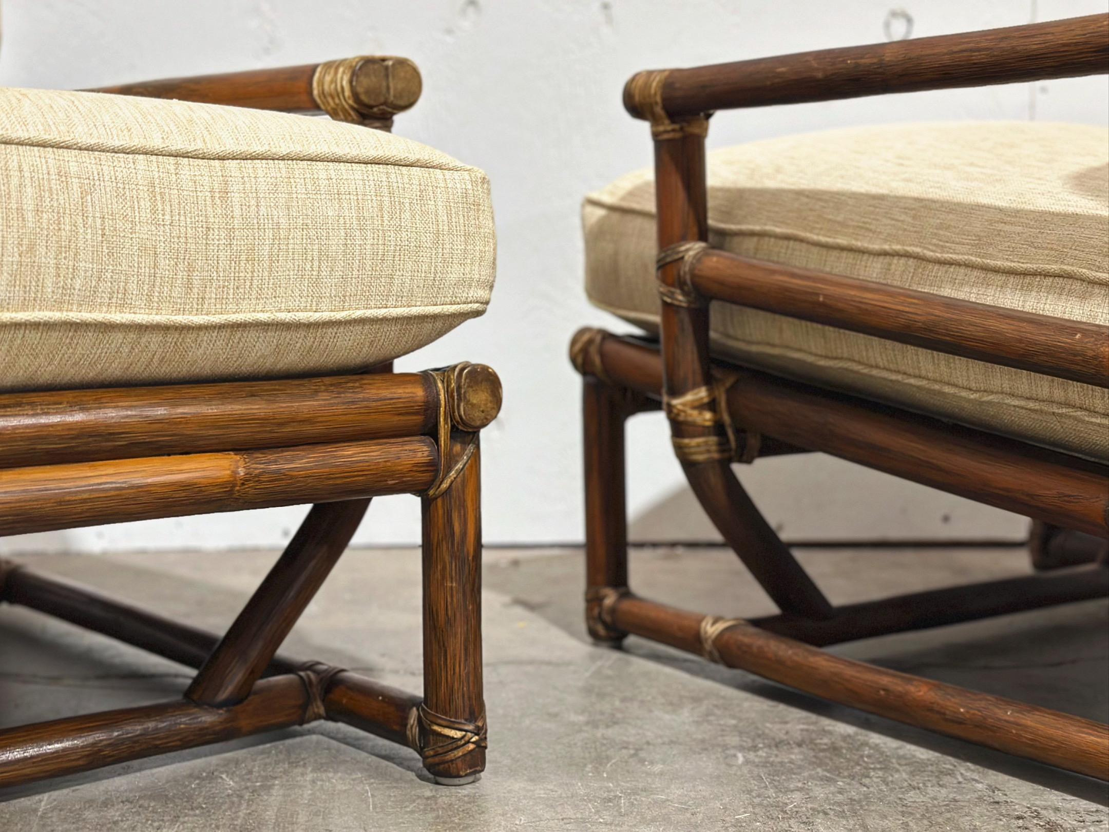 Pair of substantial mid century organic modern bamboo rattan lounge chairs by McGuire, circa 1973. Rawhide leather strapping joinery and end caps. Exquisite craftsmanship and top notch materials. Set includes two lounge chairs. Brass McGuire