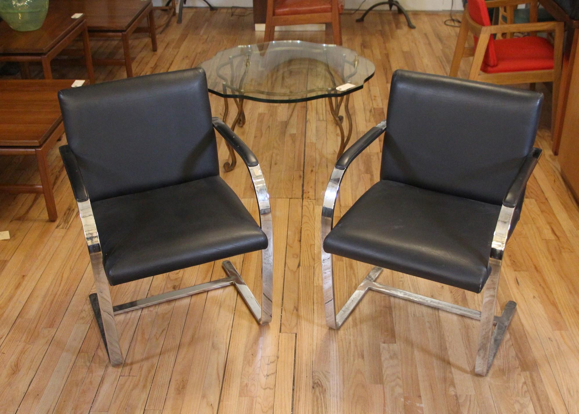 Mid-20th century pair of black leather chairs with chrome arm-rest and legs in a Mid-Century Modern style. Signed 