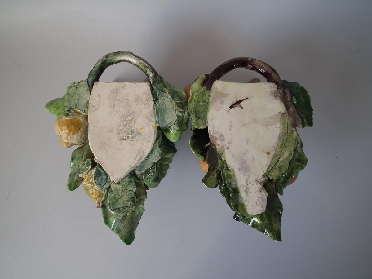 Pair of Menton Majolica wall pockets which feature a donkeys head, citrus fruits (oranges and lemons) and tree blossom. Coloration: green, orange, yellow, are predominant. The piece bears maker's marks for the Menton pottery.