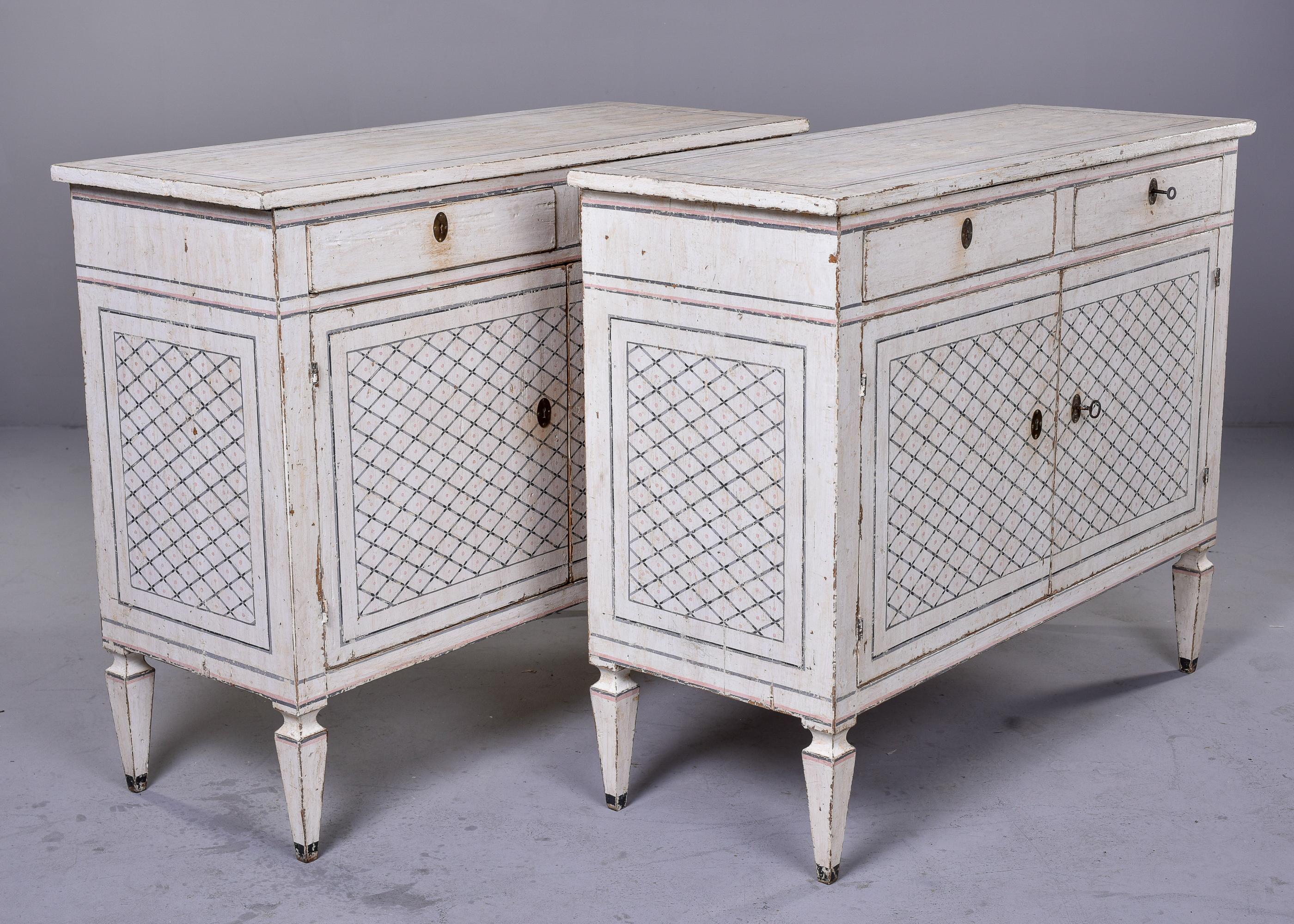 Found in Italy, this pair of cabinets from the Bologna region date from approximately the 1840s. Each cabinet has a rustic white painted finish with a painted pale gray diamond pattern on the cabinet doors and sides as well as outlined trim on the