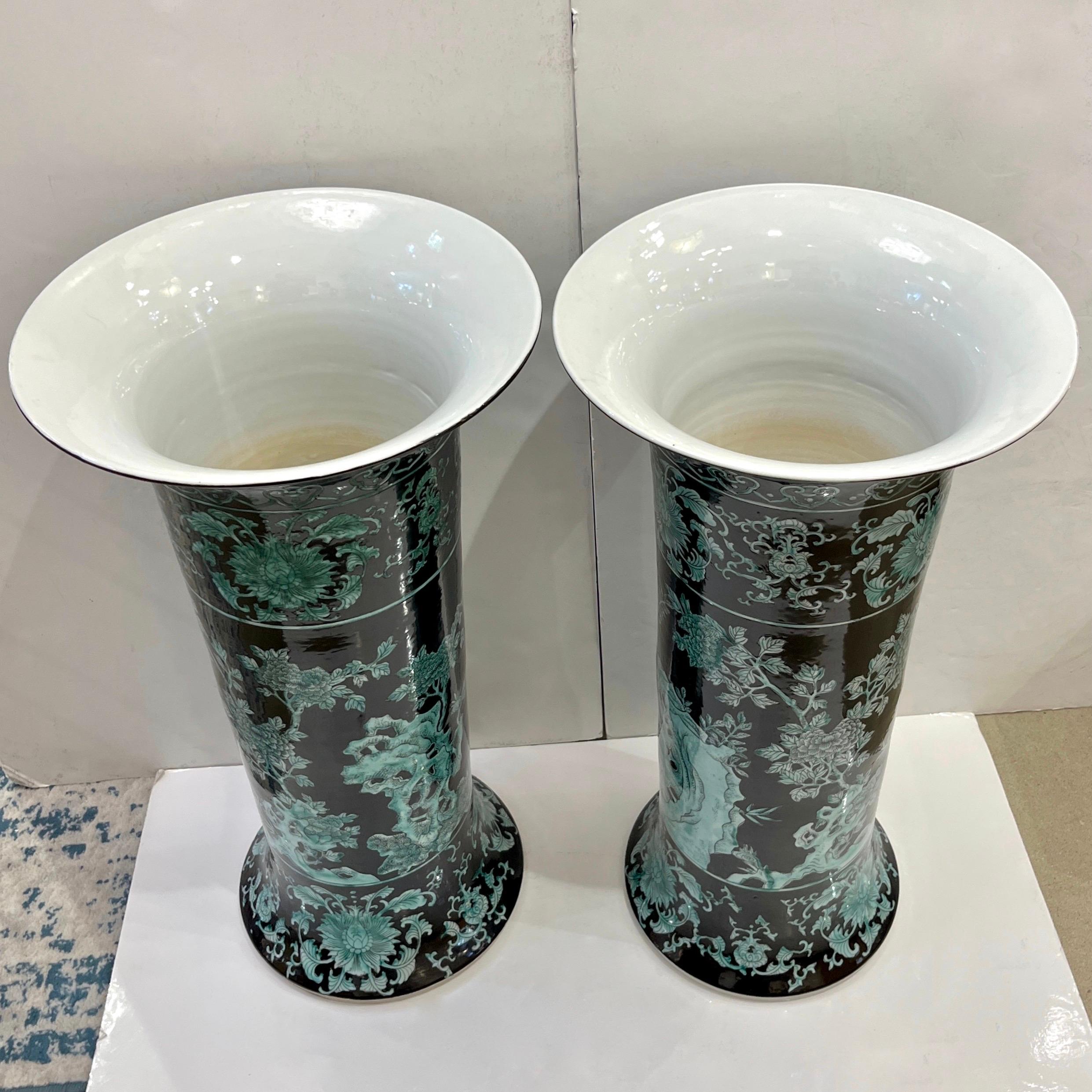 An impressive pair of vintage Chinese export jet-black and light-green tall roll vases. These monumental decorative earthenware pieces are entirely handcrafted in porcelain and enameled in traditional jet black. The decor features hand-painted