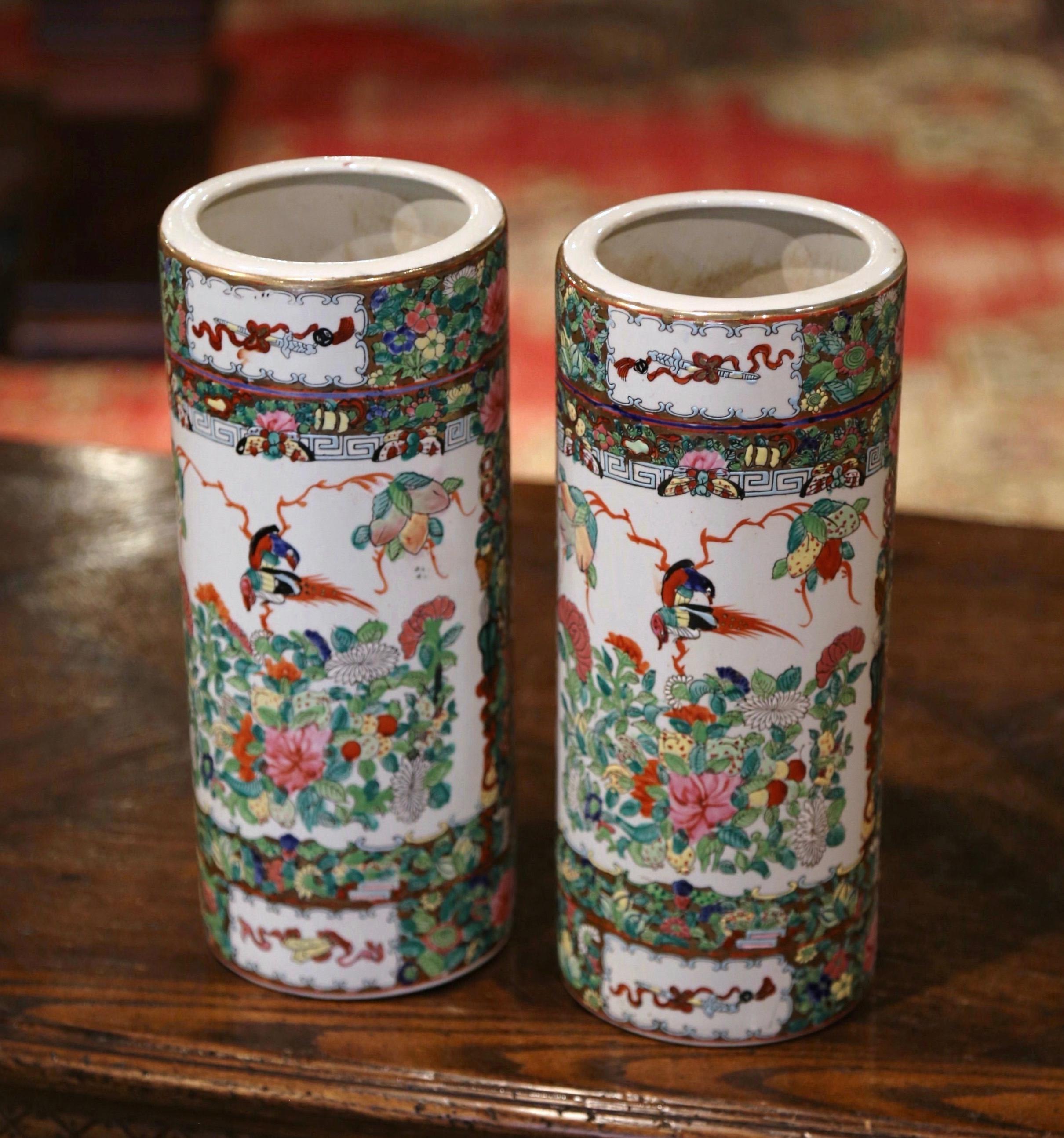 Created in China circa 1950, these colorful rose medallion stands are round in shape and feature hand painted floral reserves with birds and foliate motifs. The porcelain hat stands are in excellent condition with rich colors embellished with gilt