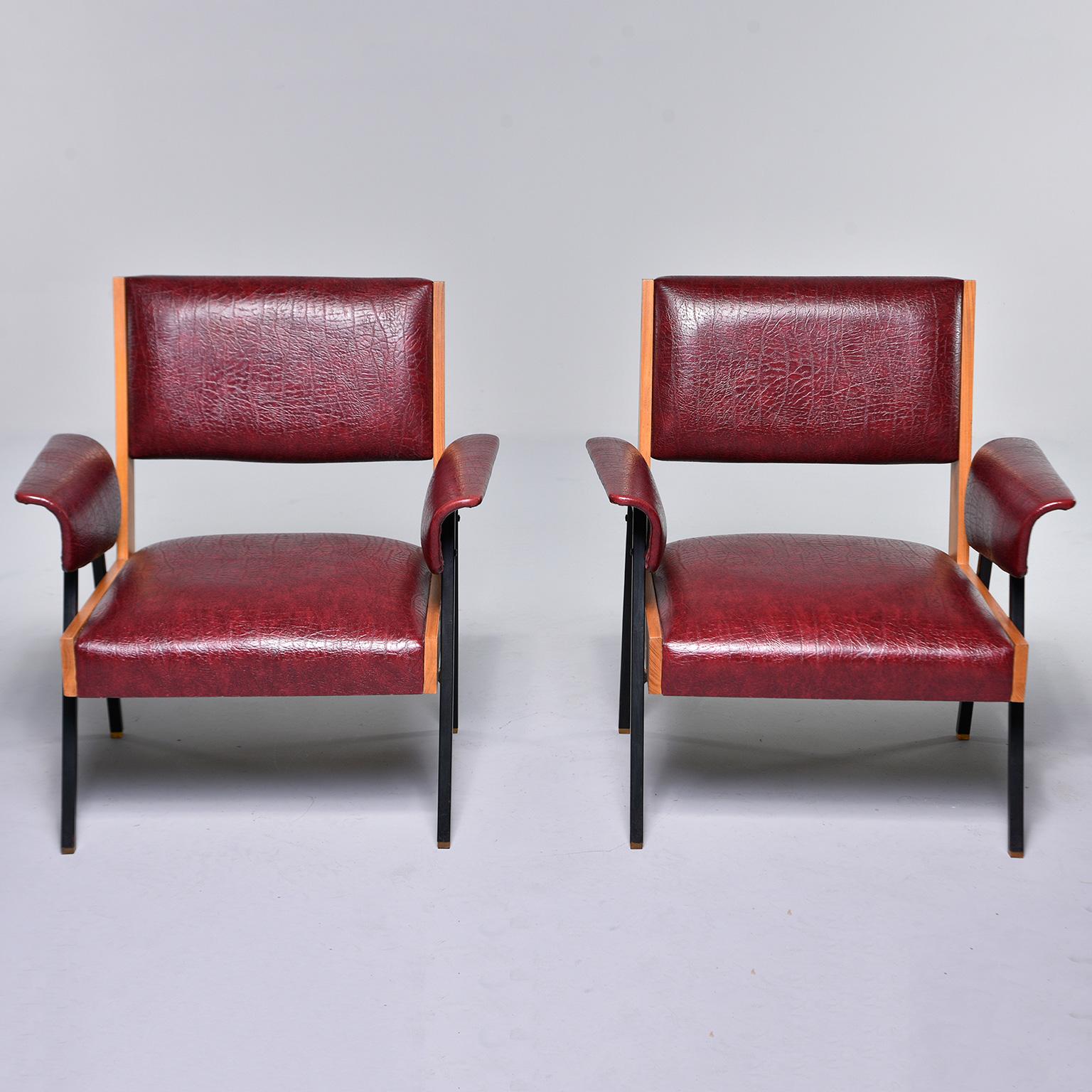 Found in Italy, this pair of circa 1960s chairs feature black metal legs, blonde wood (believed to be beech) back and side supports and bentwood armrests. Armrests, seats and backs covered in original deep red reptile-textured faux leather. 

Arm