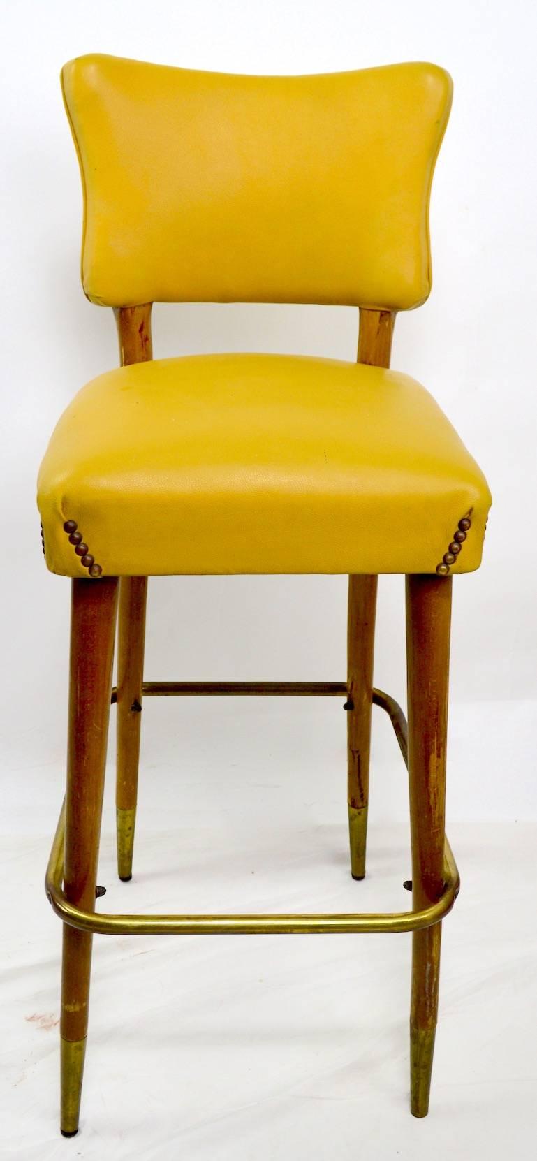 Classic Mid Century bar, counter stools with studded vinyl upholstery and wood legs. Sturdy and solid,  shows some wear to the vinyl seats and backs, wear to finish on wood elements. Seat H 29 foot rail H 12 inch.
Only one available.